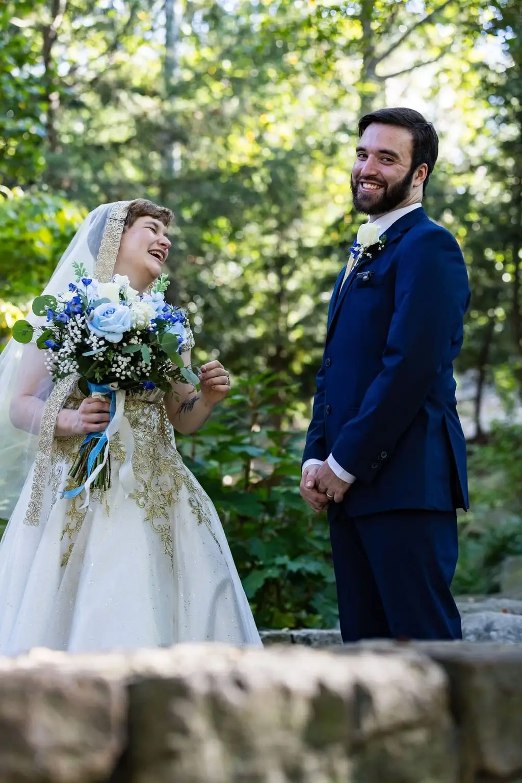 Jessica and Hayden wedding at Grand Bohemian Lodge Greenville, SC — the couple laughing together outdoors, the bride holding a blue bouquet