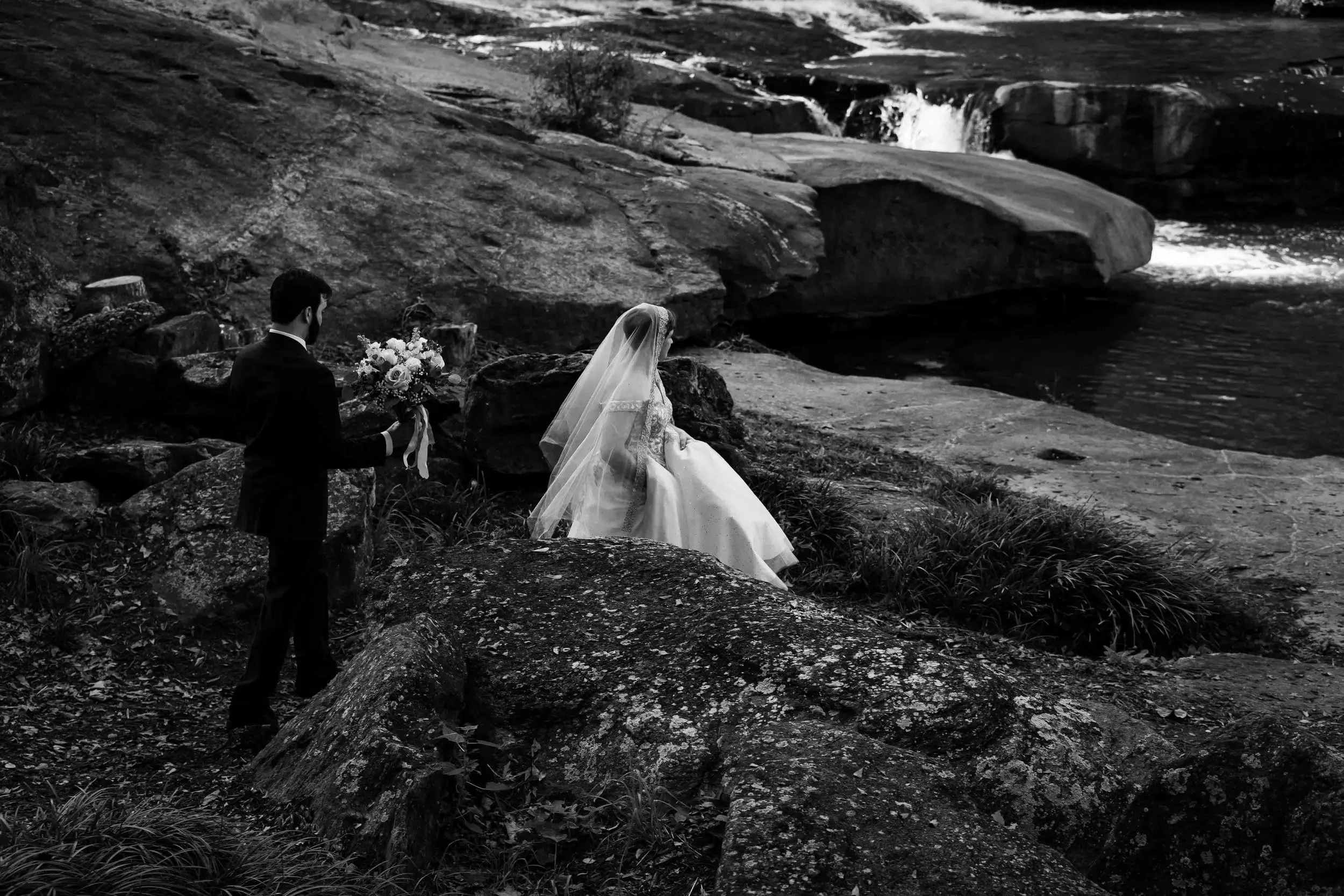 Black-and-white photo of a couple on the rocks beside a river in Greenville