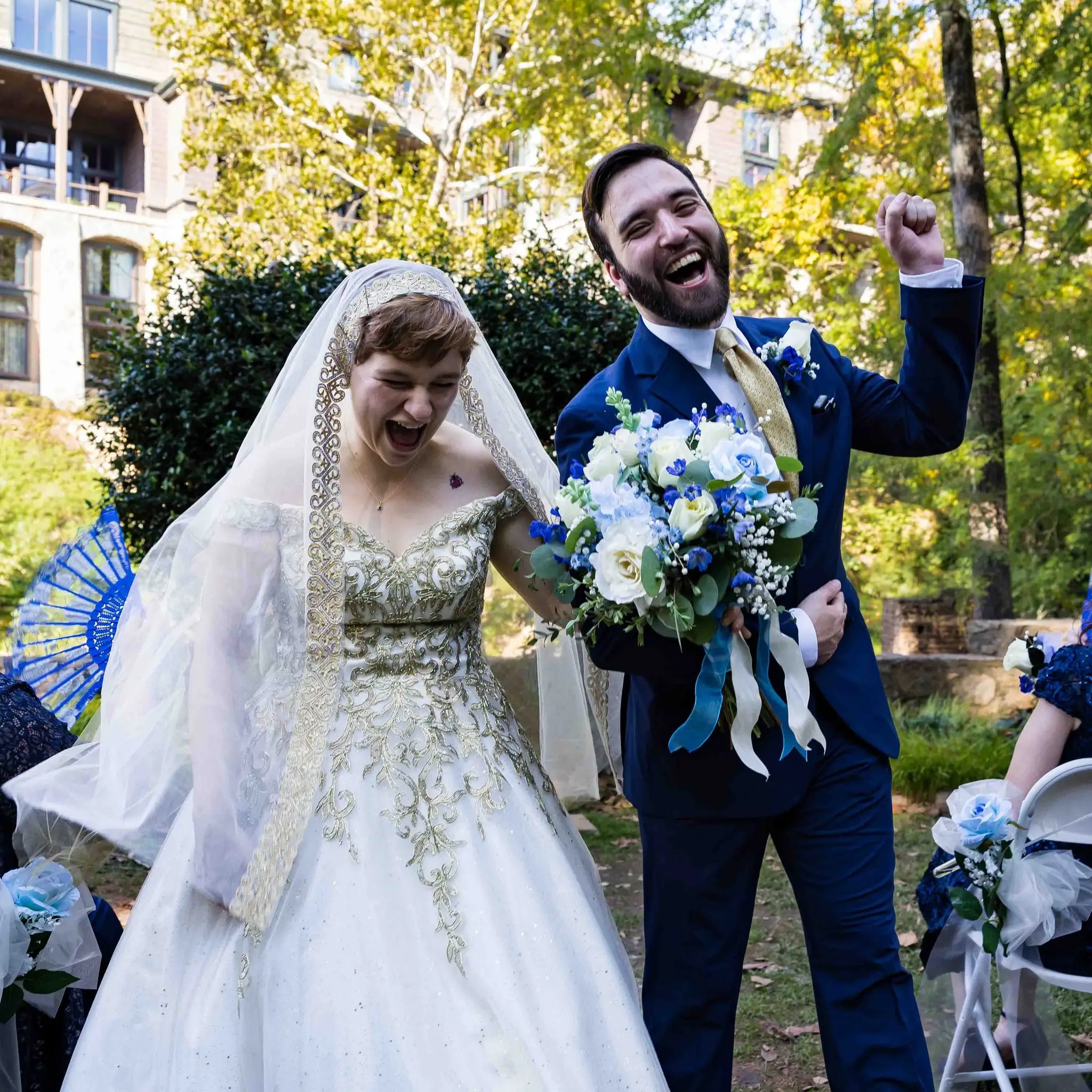 A groom raising his fist in celebration beside his laughing bride after their ceremony in Greenville
