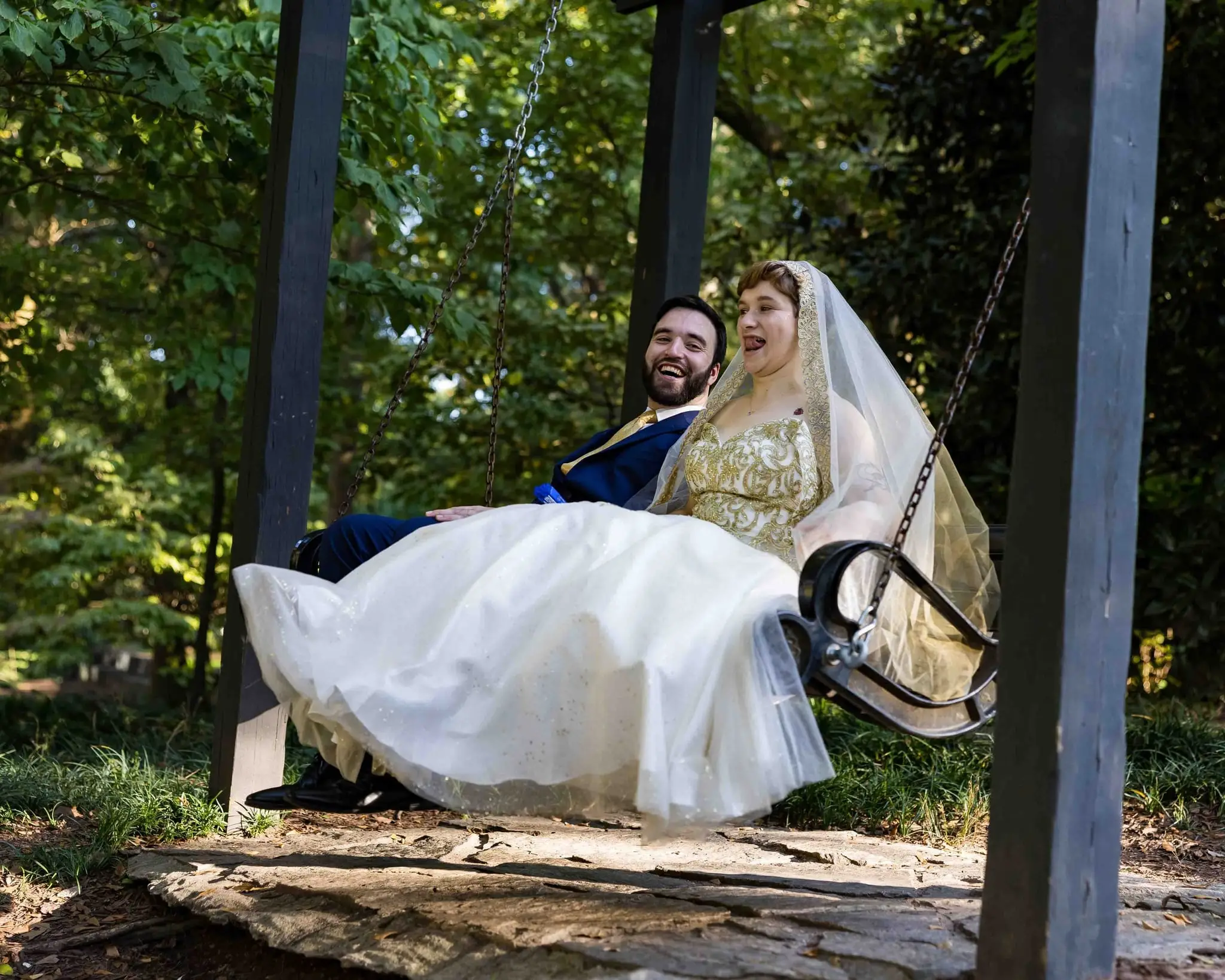 Jessica and Hayden wedding at Grand Bohemian Lodge Greenville, SC — the bride on a swing under trees with the groom beside her