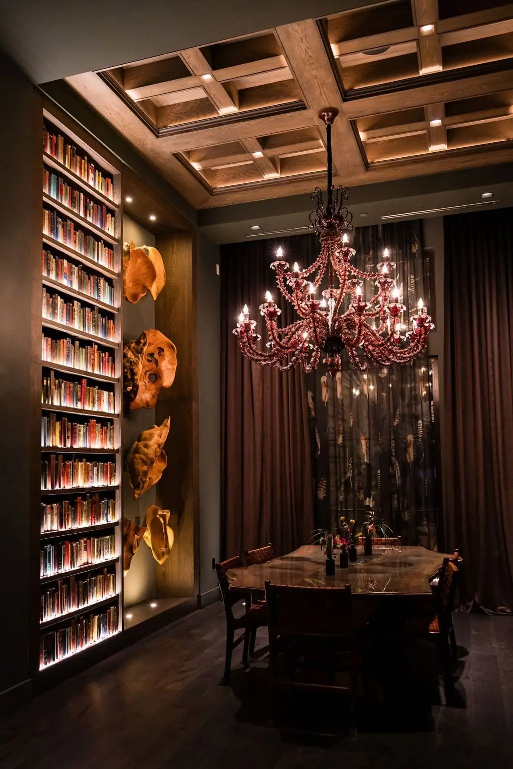 An ornate private dining room with a crystal chandelier and a backlit wine wall