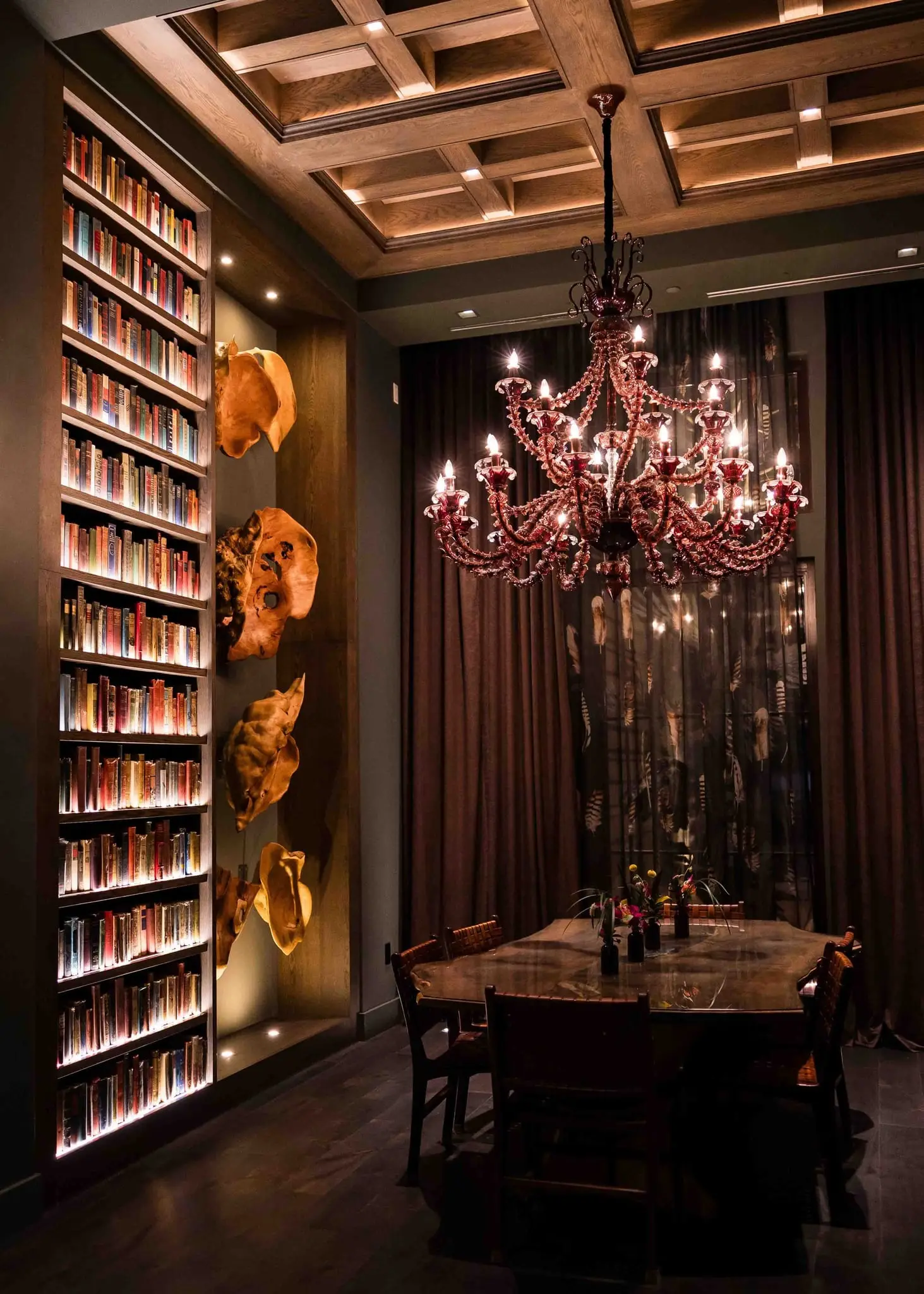 Private dining room with a tall bookshelf wall and a red glass chandelier at the Grand Bohemian Lodge Greenville