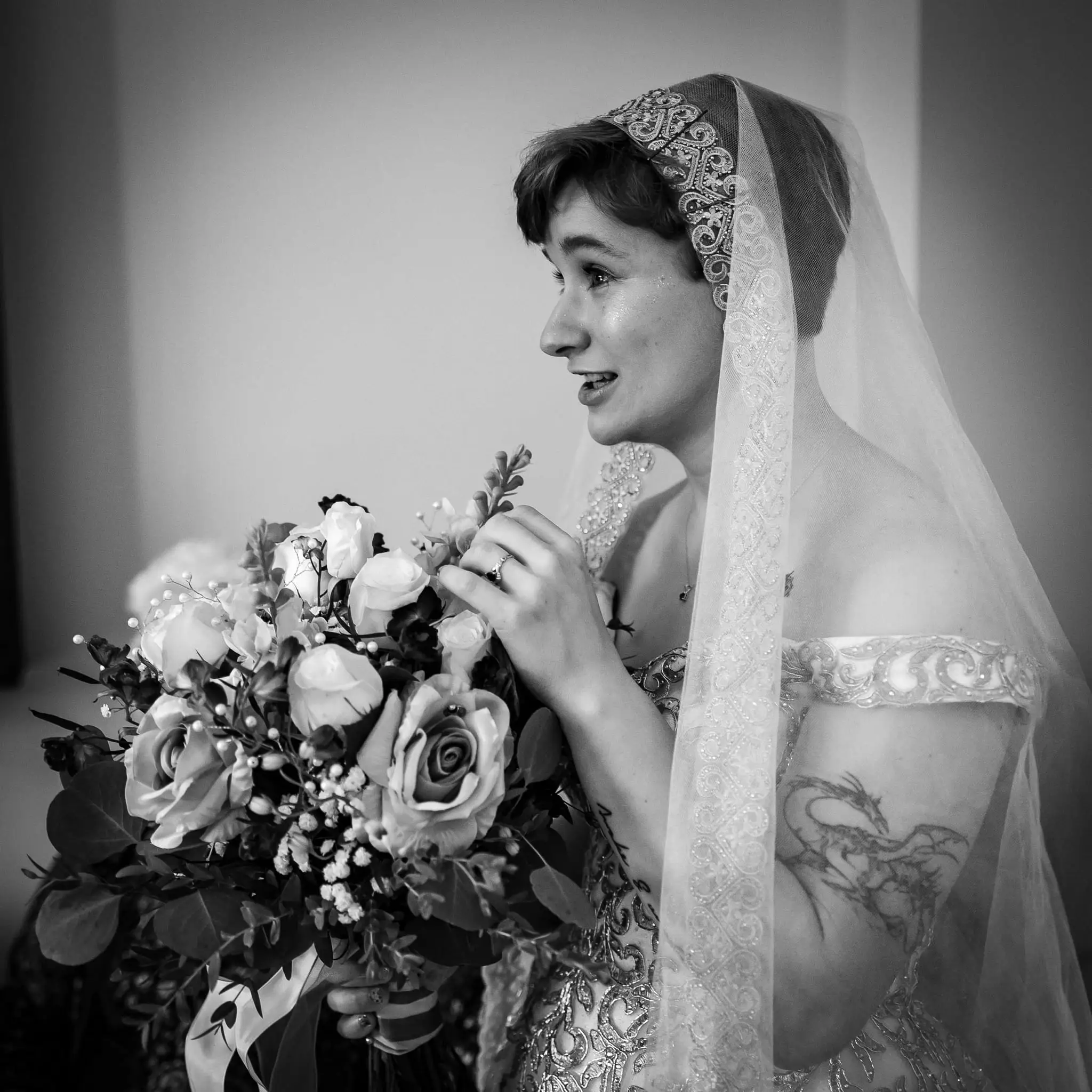 Jessica and Hayden wedding at Grand Bohemian Lodge Greenville, SC — the bride in a lace veil holding a bouquet and looking toward a window, black and white