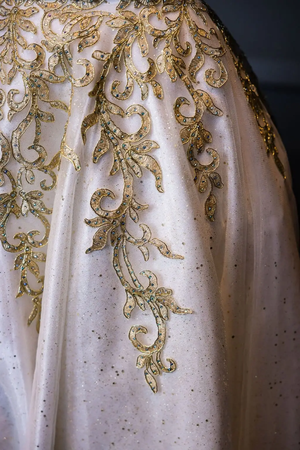 Close-up of gold bead embroidery scrolling across the sparkling tulle skirt