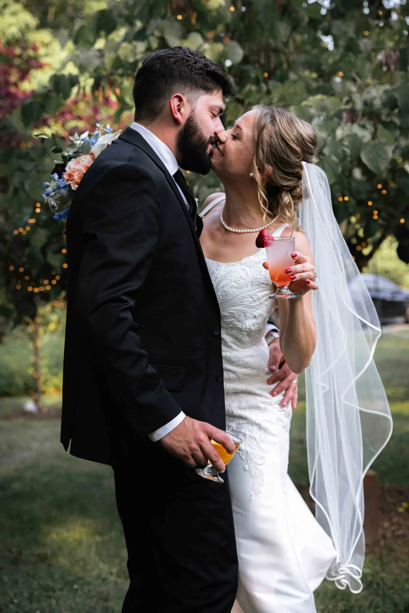 Anna and Joseph wedding at The Crest Center & Pavilion, Asheville NC — the couple kissing outdoors, each holding a cocktail