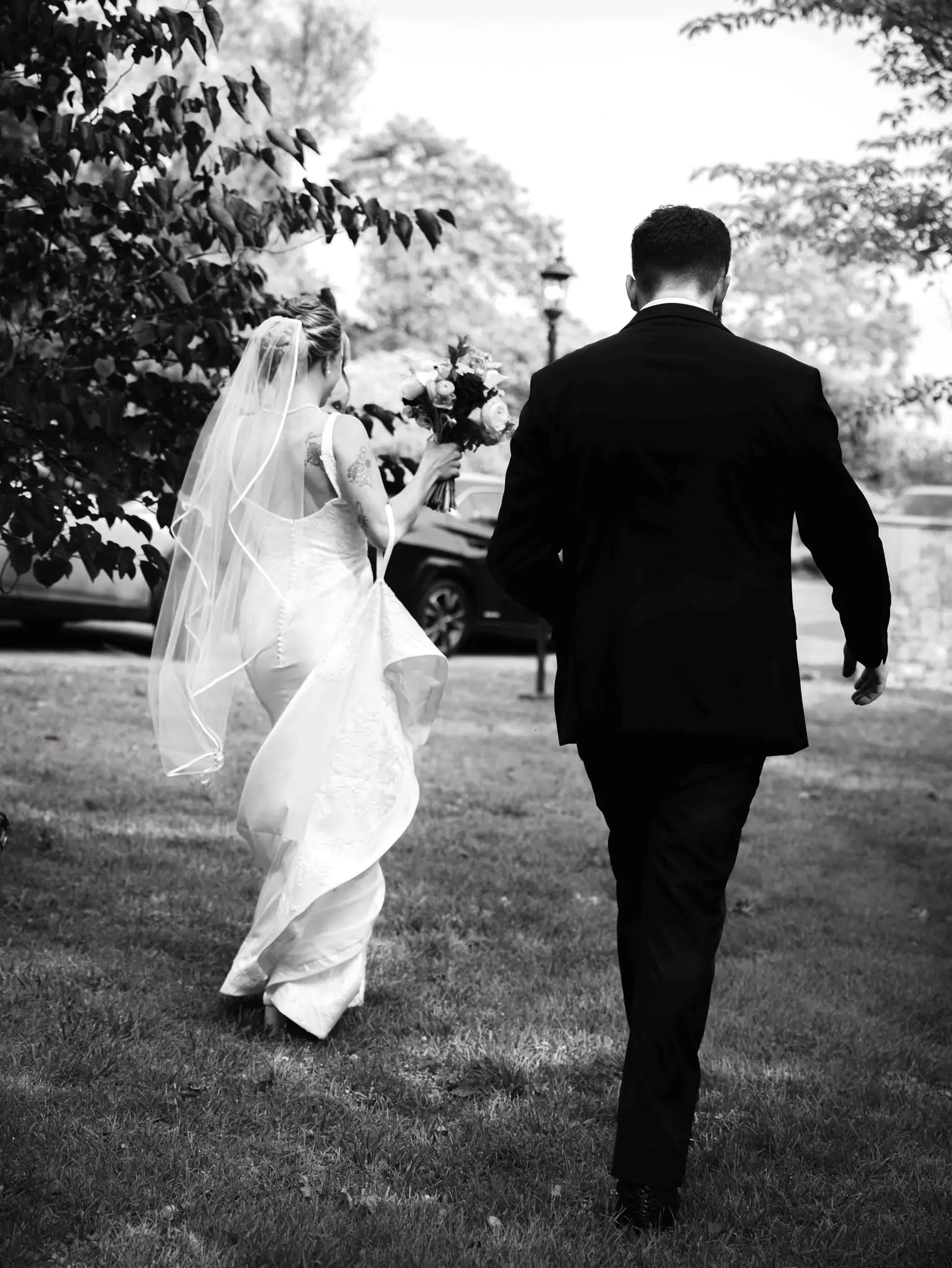 Anna and Joseph wedding at The Crest Center & Pavilion, Asheville NC — the couple walking away from the camera across a lawn, black and white