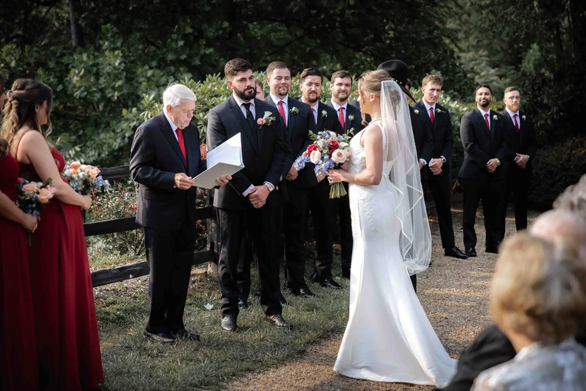 Anna and Joseph wedding at The Crest Center & Pavilion, Asheville NC — the couple at the ceremony with the officiant and the wedding party lined up on the path