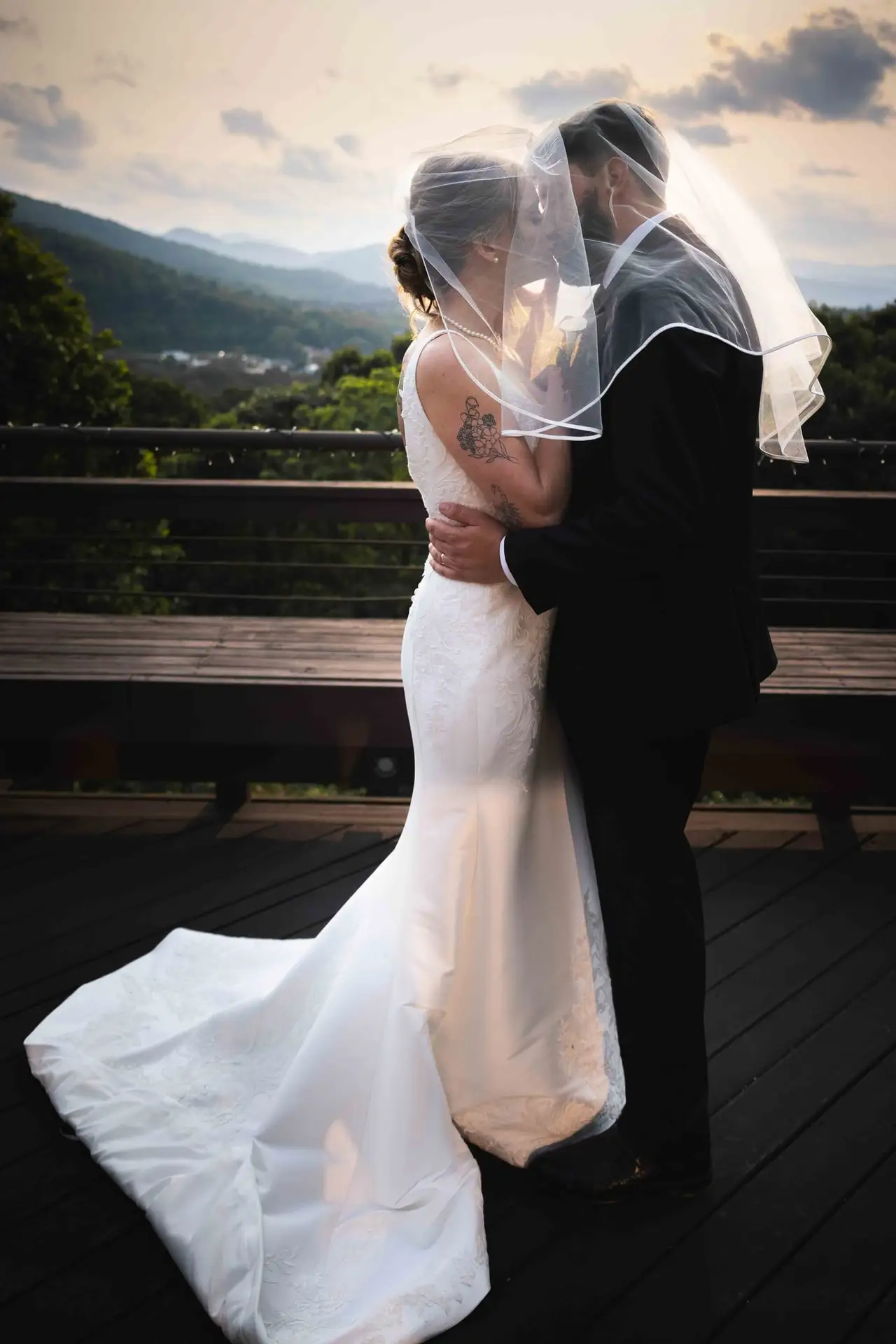 Anna and Joseph wedding at The Crest Center & Pavilion, Asheville NC — the couple embracing under the bride's veil with mountains and sunset glow behind