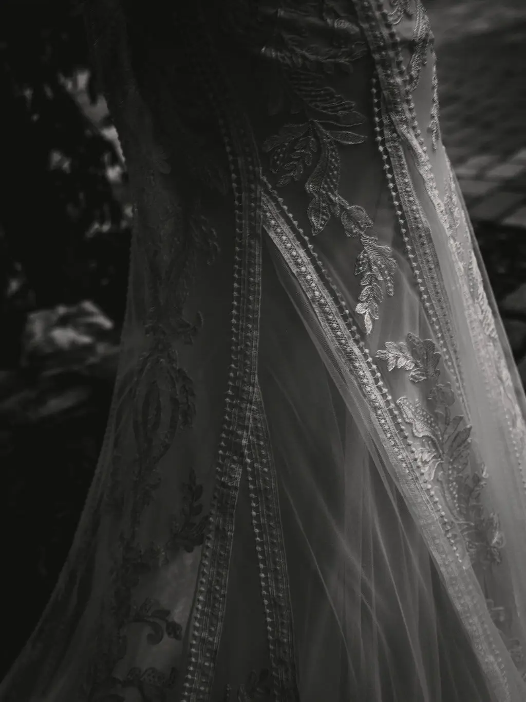 Black and white detail of beaded lace on the bride's wedding gown
