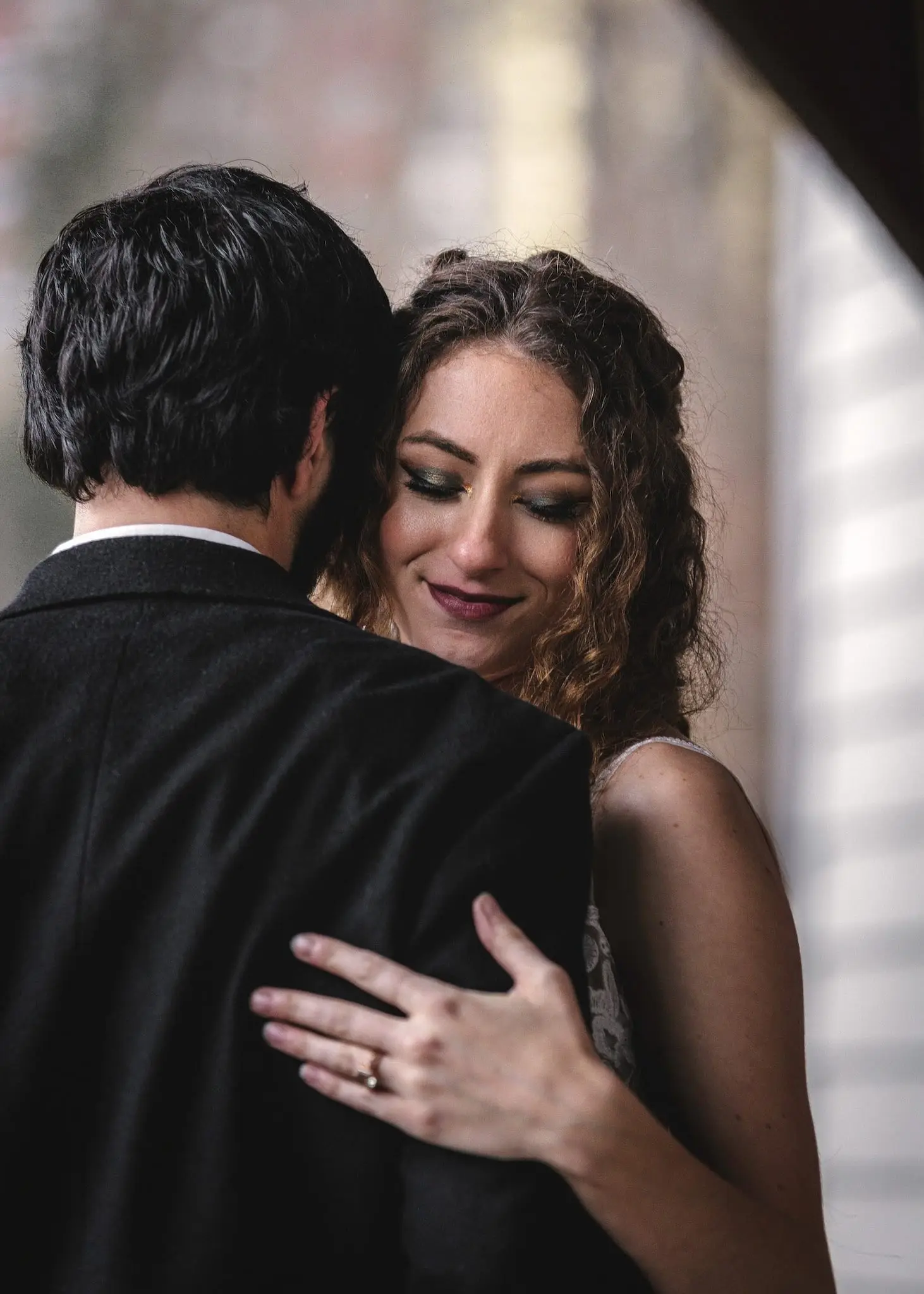 Julia smiles with her eyes closed as Joe holds her close, her ring hand on his shoulder