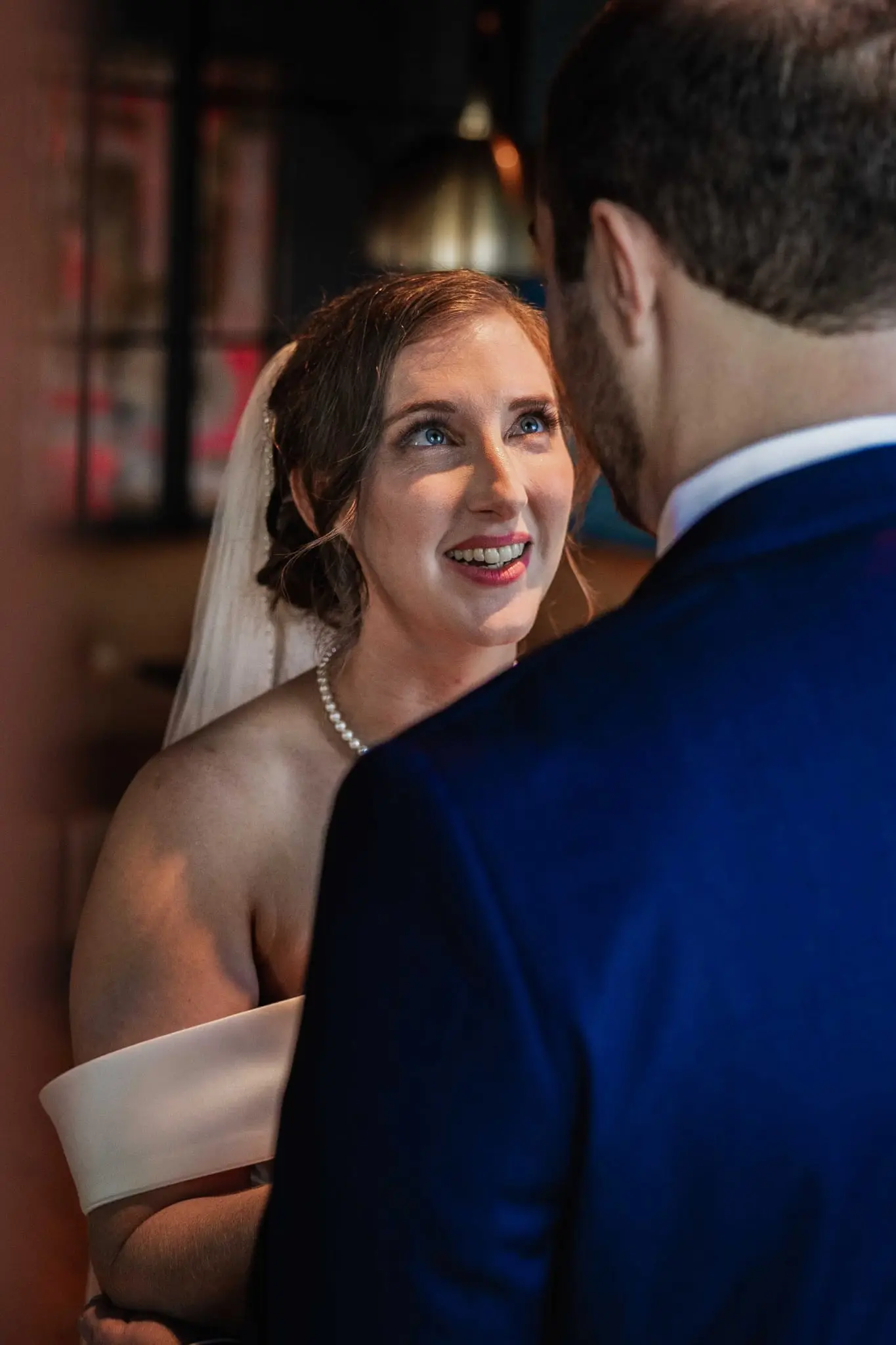 Bride beaming up at the groom, her veil visible, in a close first look portrait