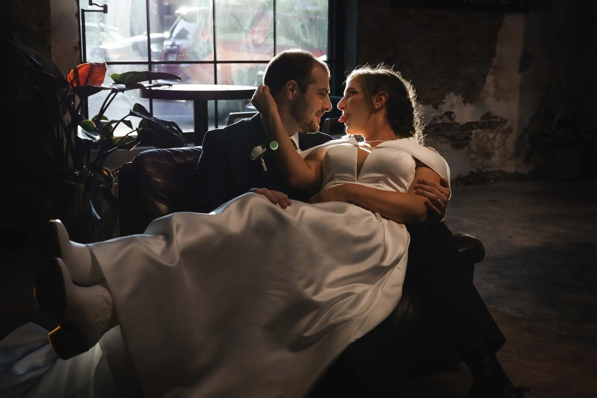 Ashley and Alex wedding at Conrad Nashville, Nashville TN — the couple lounging in a dark chair, her gown spread over his lap