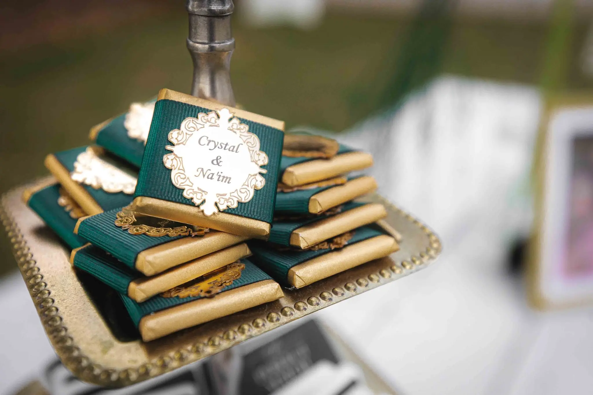 Gold-wrapped green chocolates labeled Crystal & Na'im on a gold tray