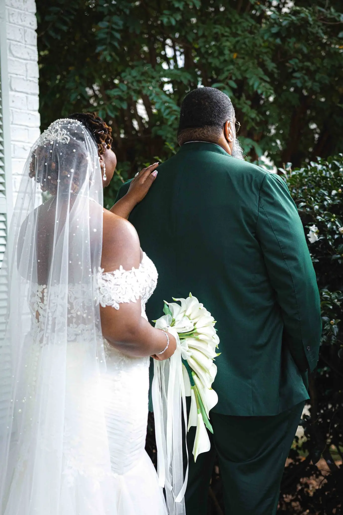 Bride touching the groom's shoulder from behind as he faces away for the first look