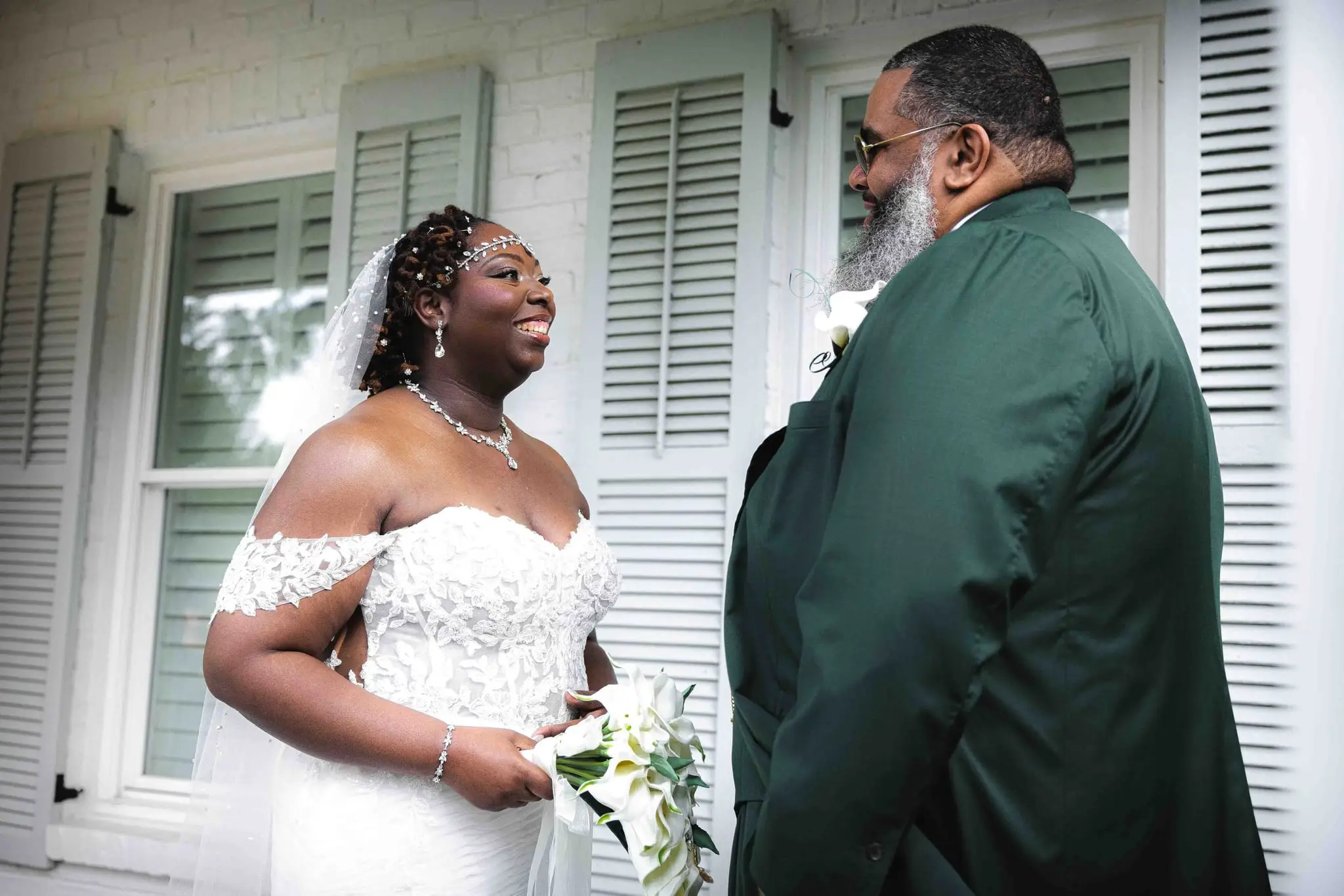 Crystal smiling at the groom as the first look begins, her white calla lily bouquet in hand