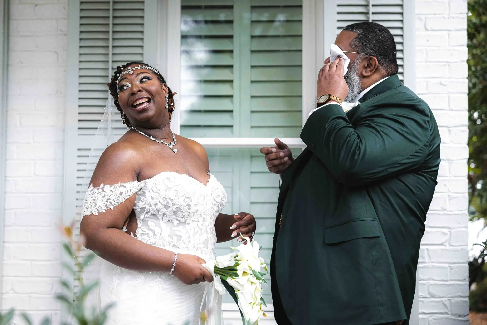 Bride laughing while the groom wipes away tears during their first look