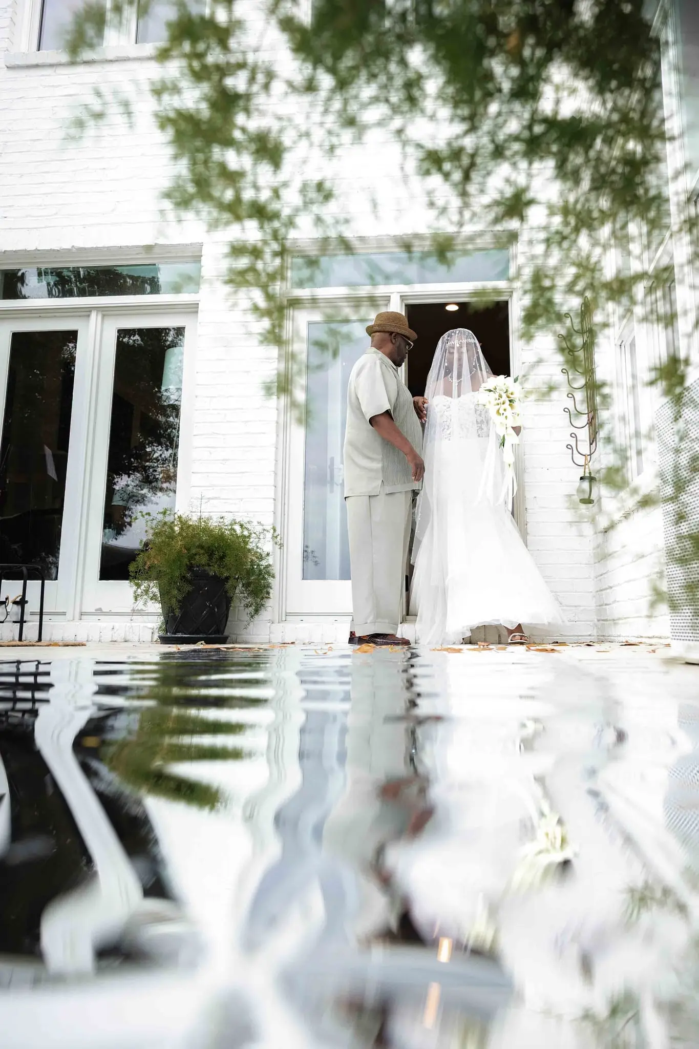 Bride and her escort at the white house doors before the aisle walk, reflected in a glossy mirrored aisle
