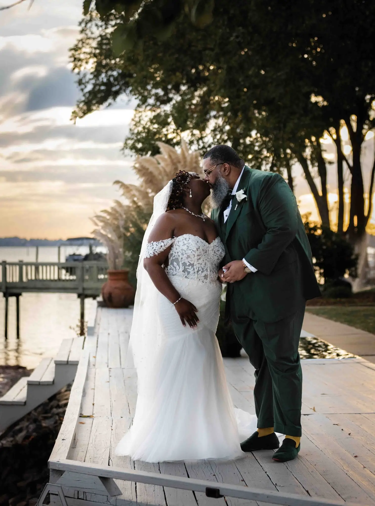 Crystal and Na'im kissing on the lakeside dock at sunset, her veil trailing