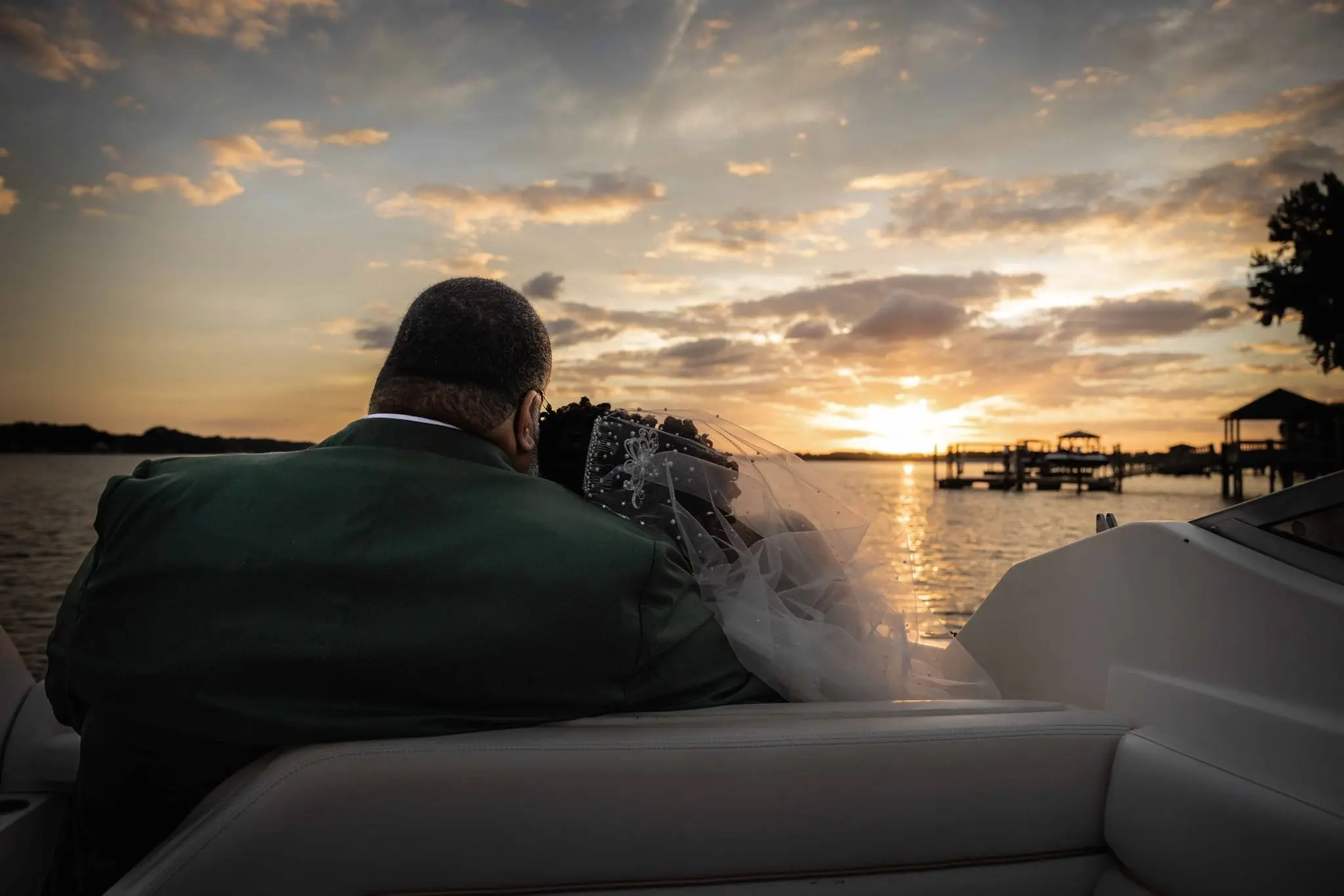 Couple seen from behind on a boat watching the sun set over the lake