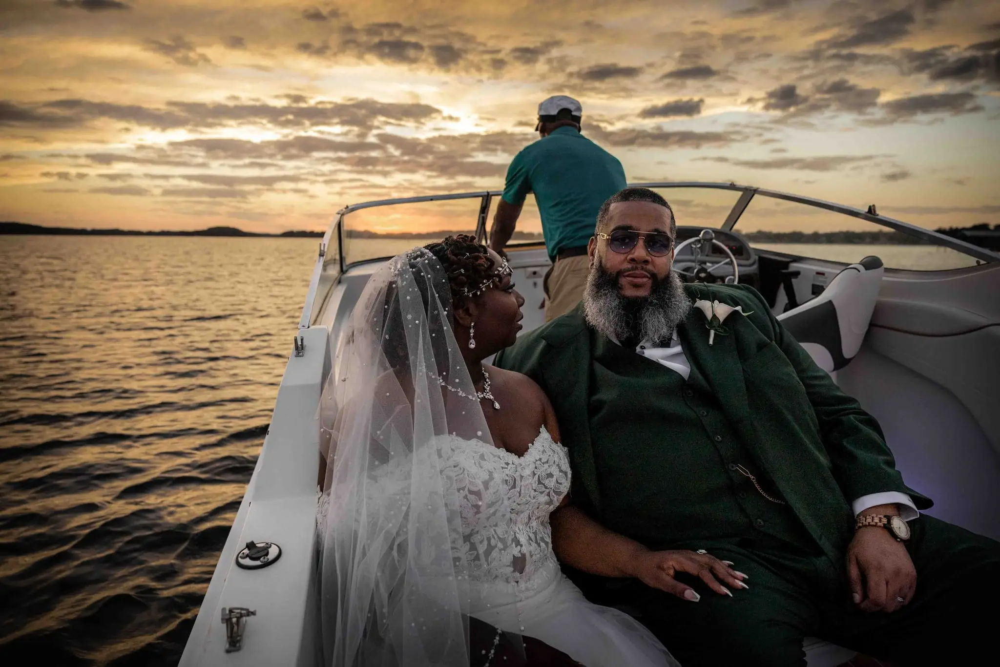 Crystal and Na'im sitting close in the back of a boat on a golden-hour lake cruise
