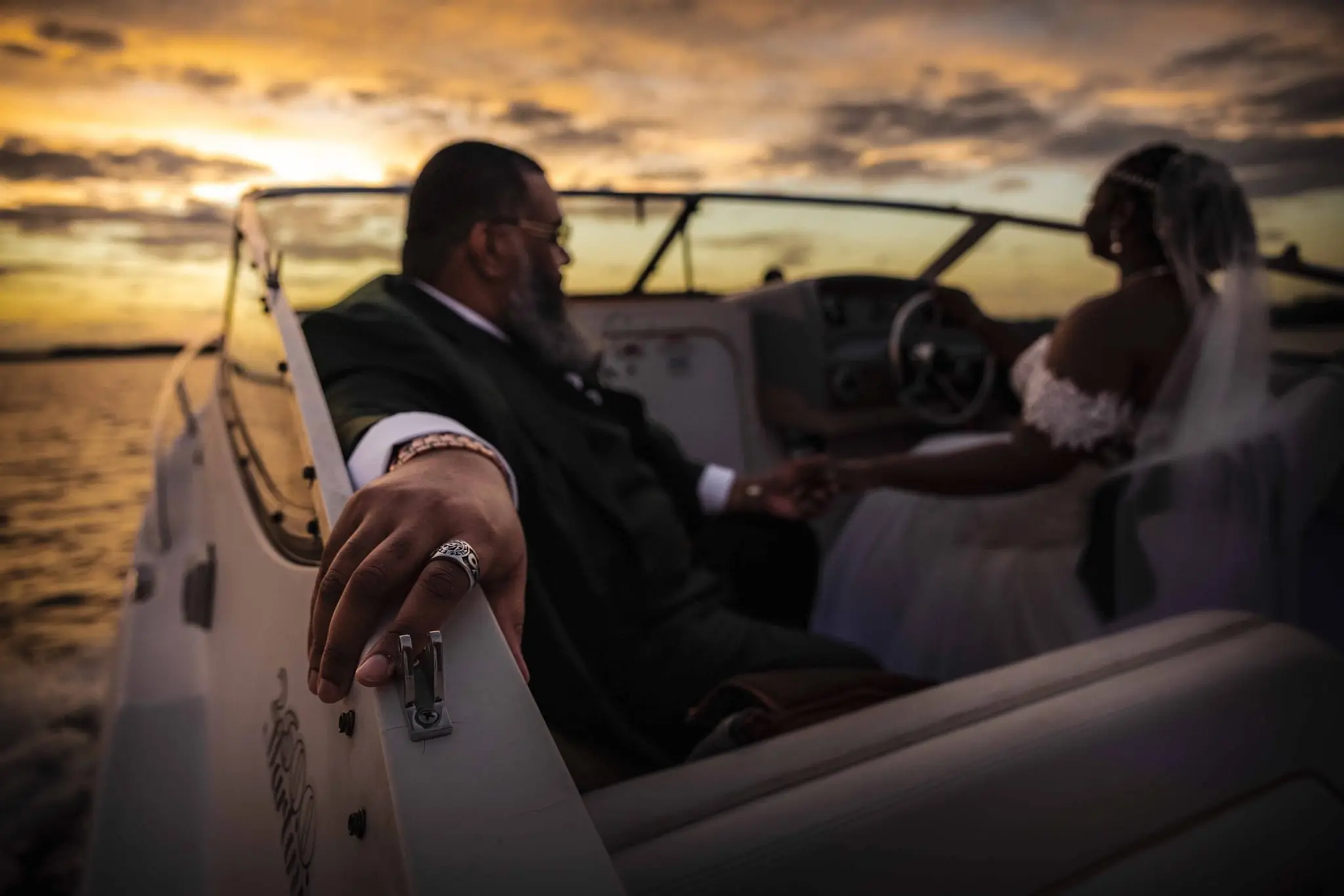 Low-angle view of the couple holding hands in the boat with a golden sunset behind