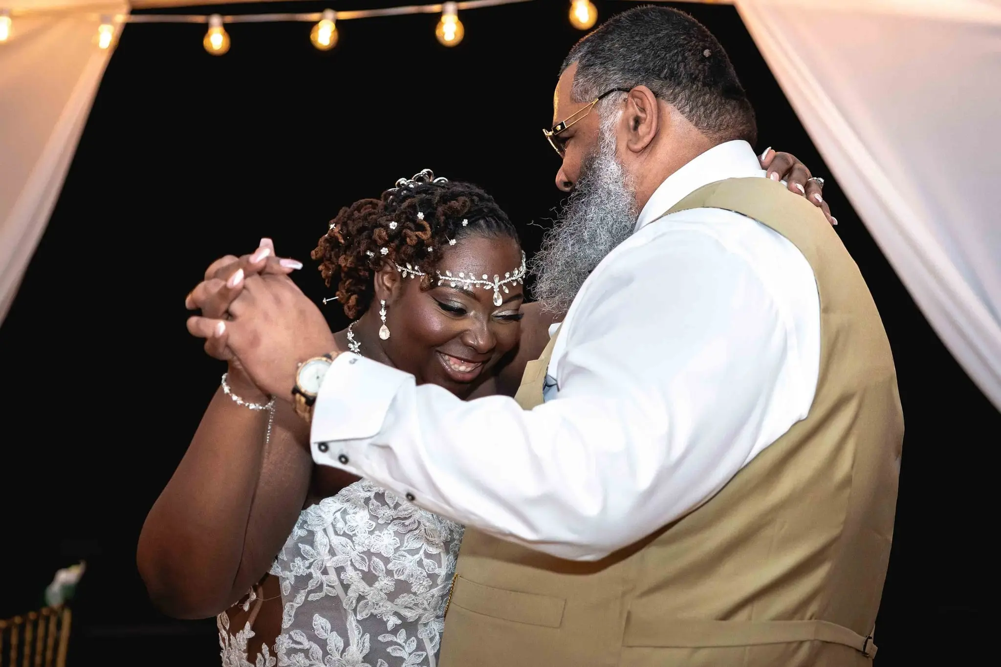 Crystal and Na'im dancing hand in hand, smiling beneath cafe lights at the reception