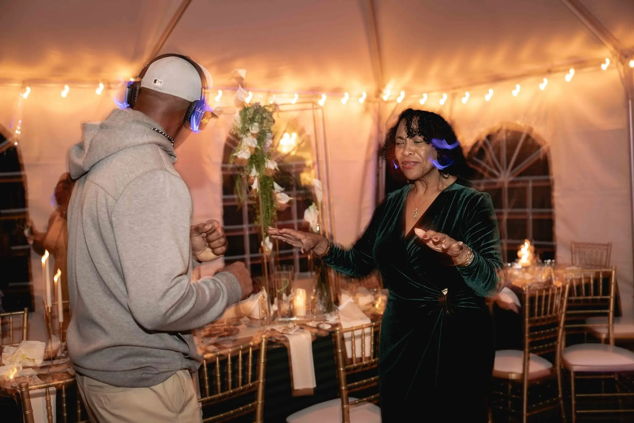 Man in a gray hoodie and woman in a green velvet dress dancing at the silent disco