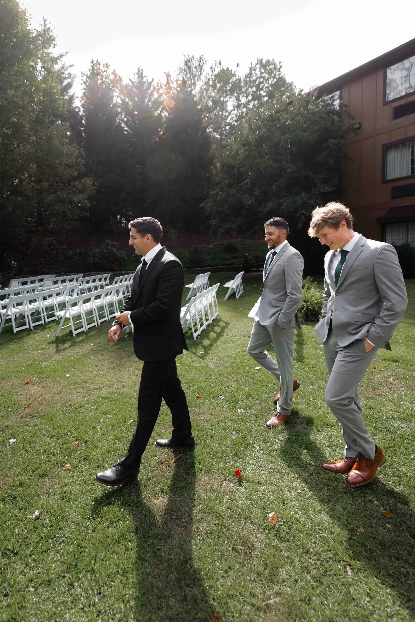 Lauren and Damian wedding at The Lodge at Flat Rock, Flat Rock NC — the groom and groomsmen walking past rows of white chairs on the lawn