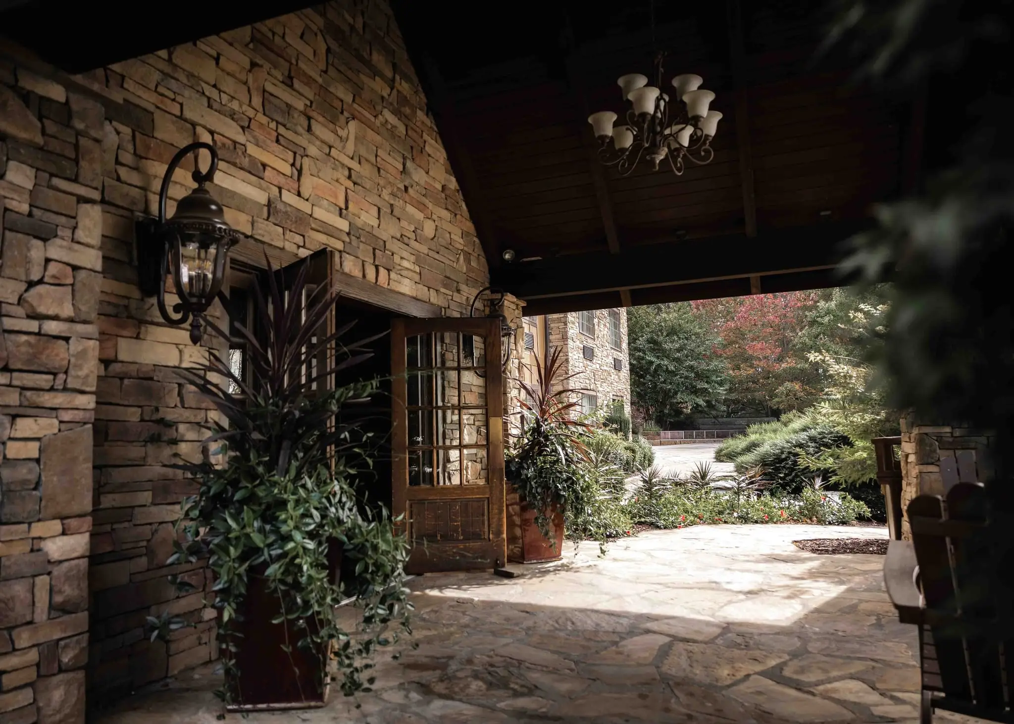 Lauren and Damian wedding at The Lodge at Flat Rock, Flat Rock NC — a stone-walled courtyard entrance with a lantern and potted plants