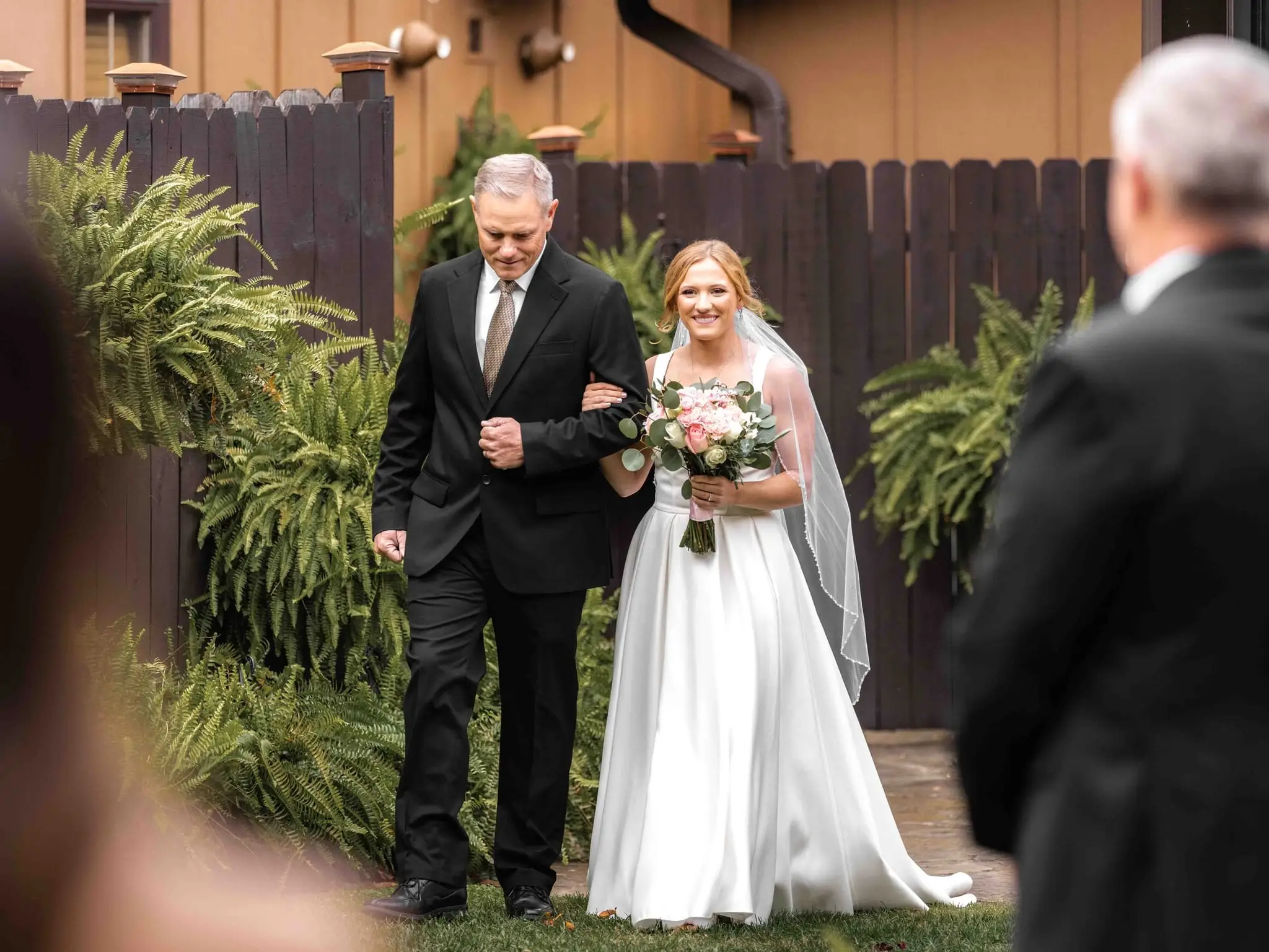Lauren and Damian wedding at The Lodge at Flat Rock, Flat Rock NC — a man in a dark suit walking the bride toward the ceremony