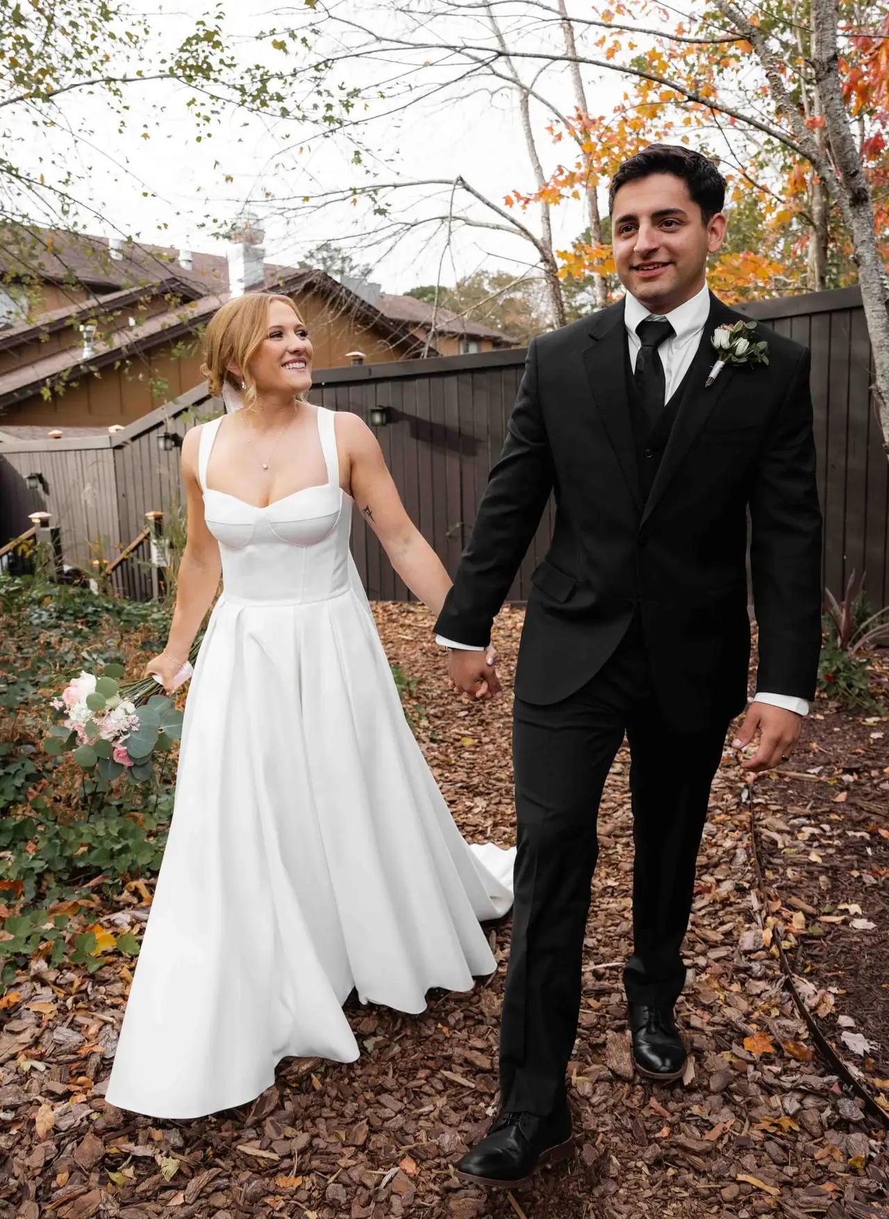 Lauren and Damian wedding at The Lodge at Flat Rock, Flat Rock NC — the couple walking hand in hand through fallen autumn leaves