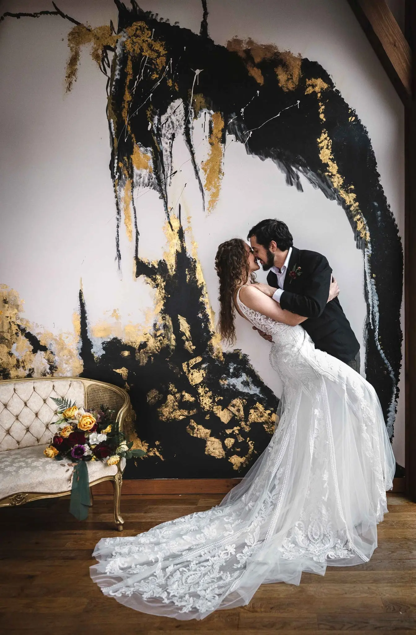 Joe and Julia in a dip pose against a gold and black marbled wall at Haiku I Do