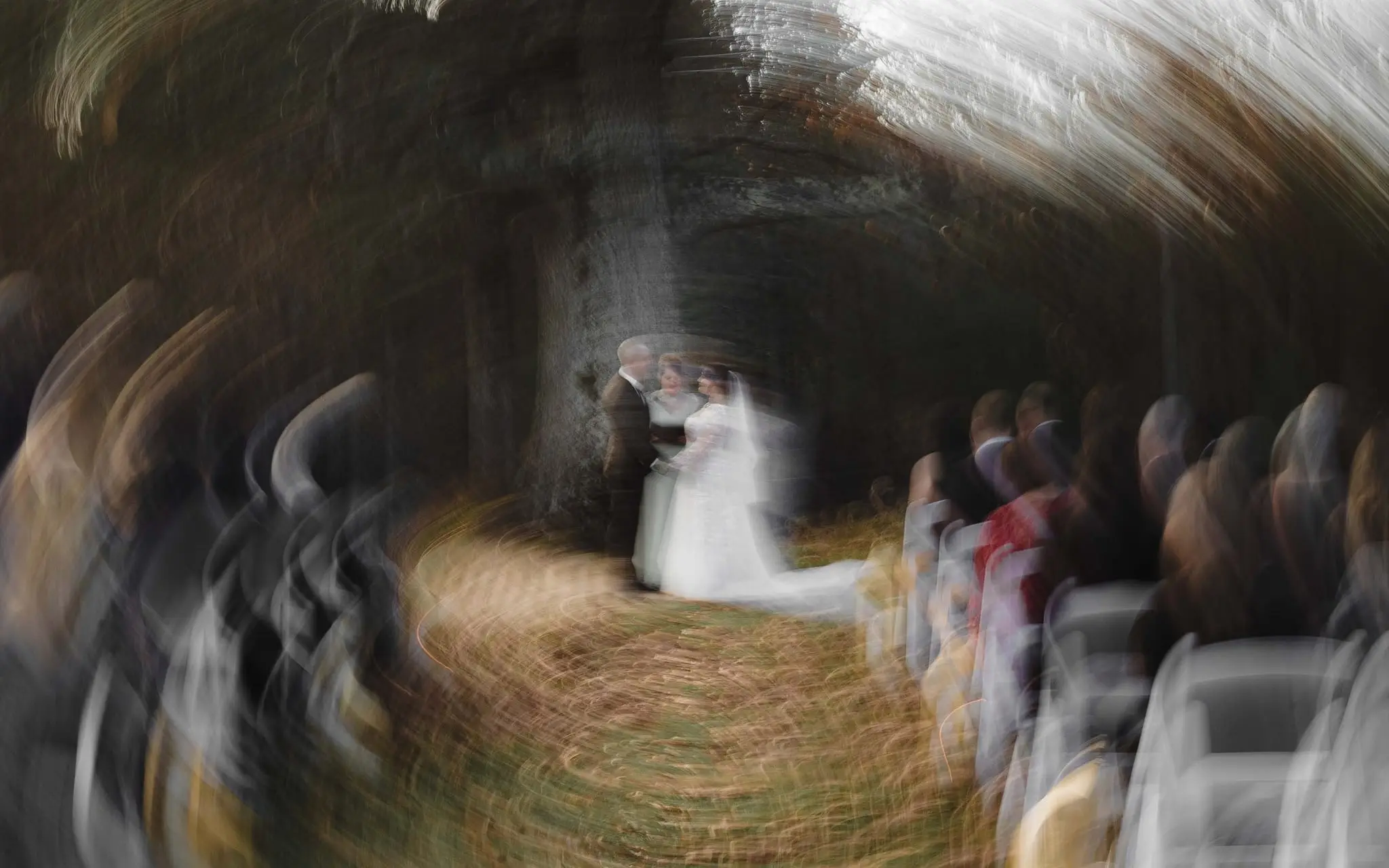 Swirling motion blur of the ceremony with the couple at center and guests in white chairs