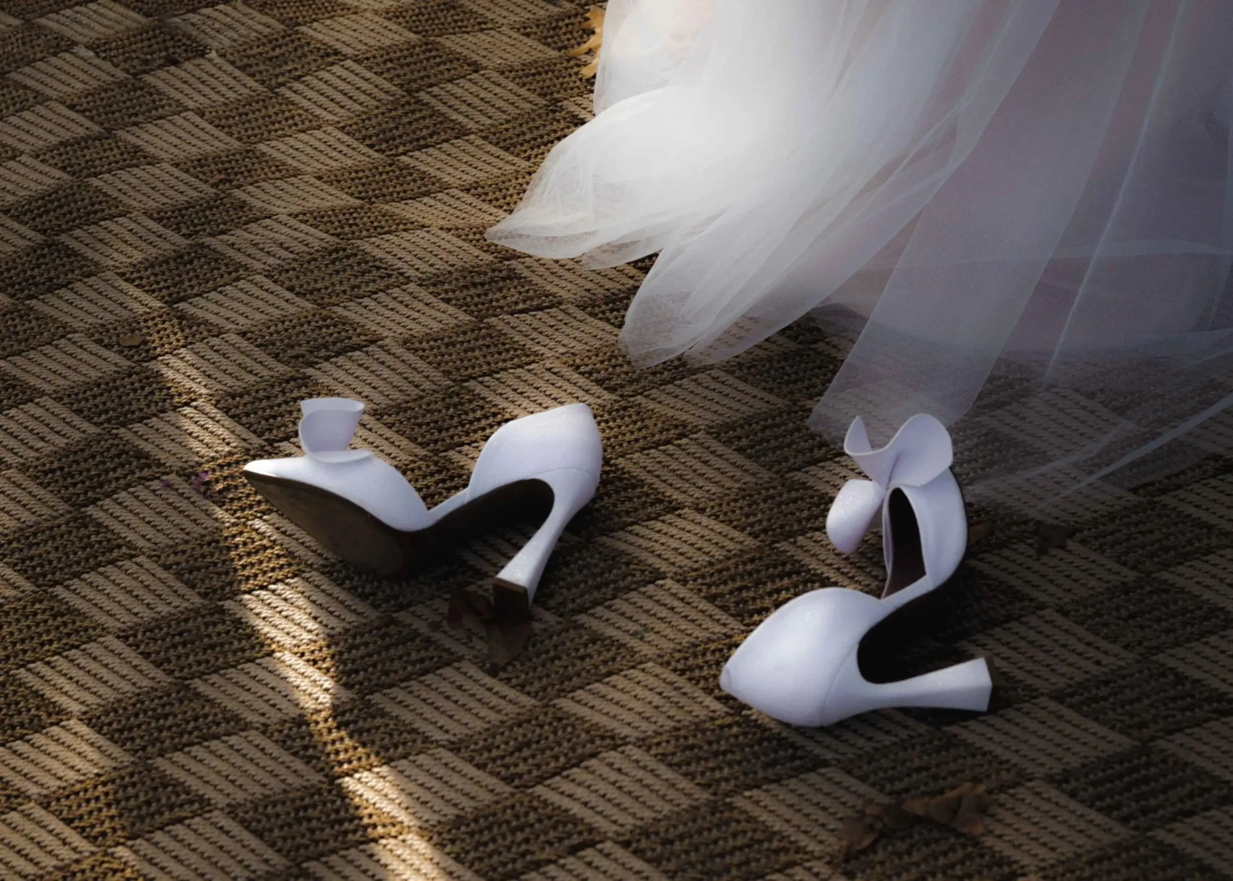 White heels kicked off on a woven rug