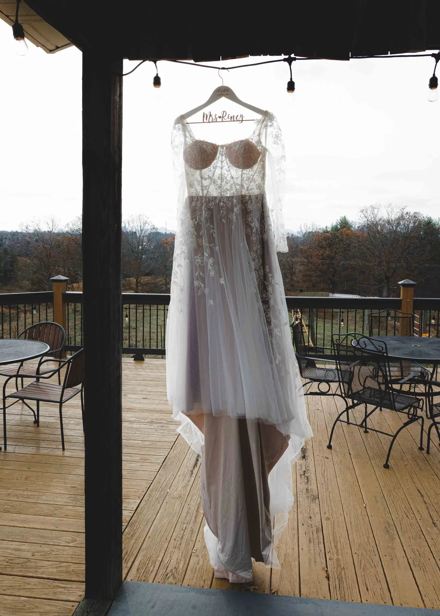 Wedding dress with a Mrs. hanger hanging on a deck overlooking the hills at Emerald Ridge Farm
