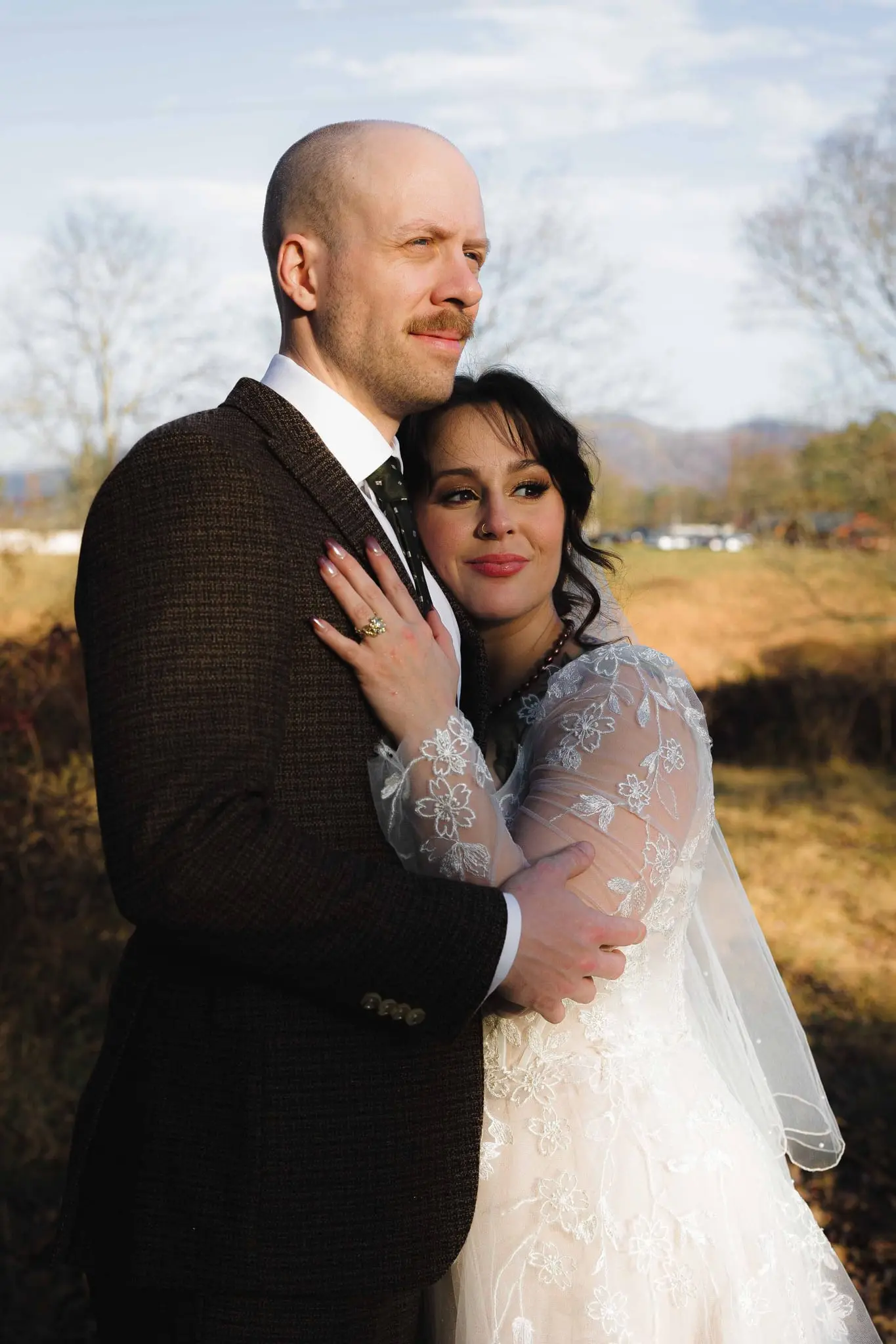 Bride rests her head on the groom's chest as they look out over the Weaverville hills