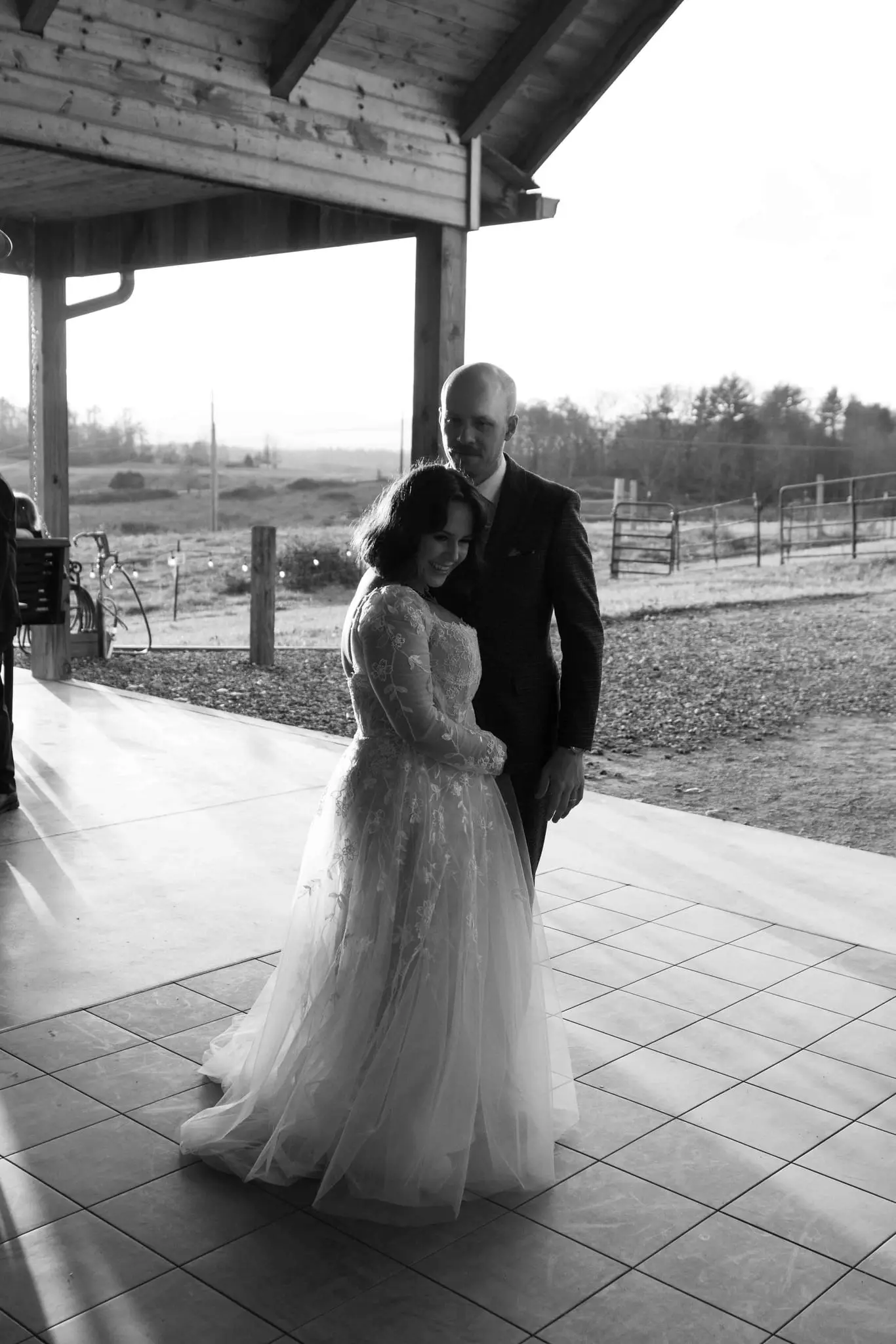 Black and white first dance on a covered patio with farm fields beyond