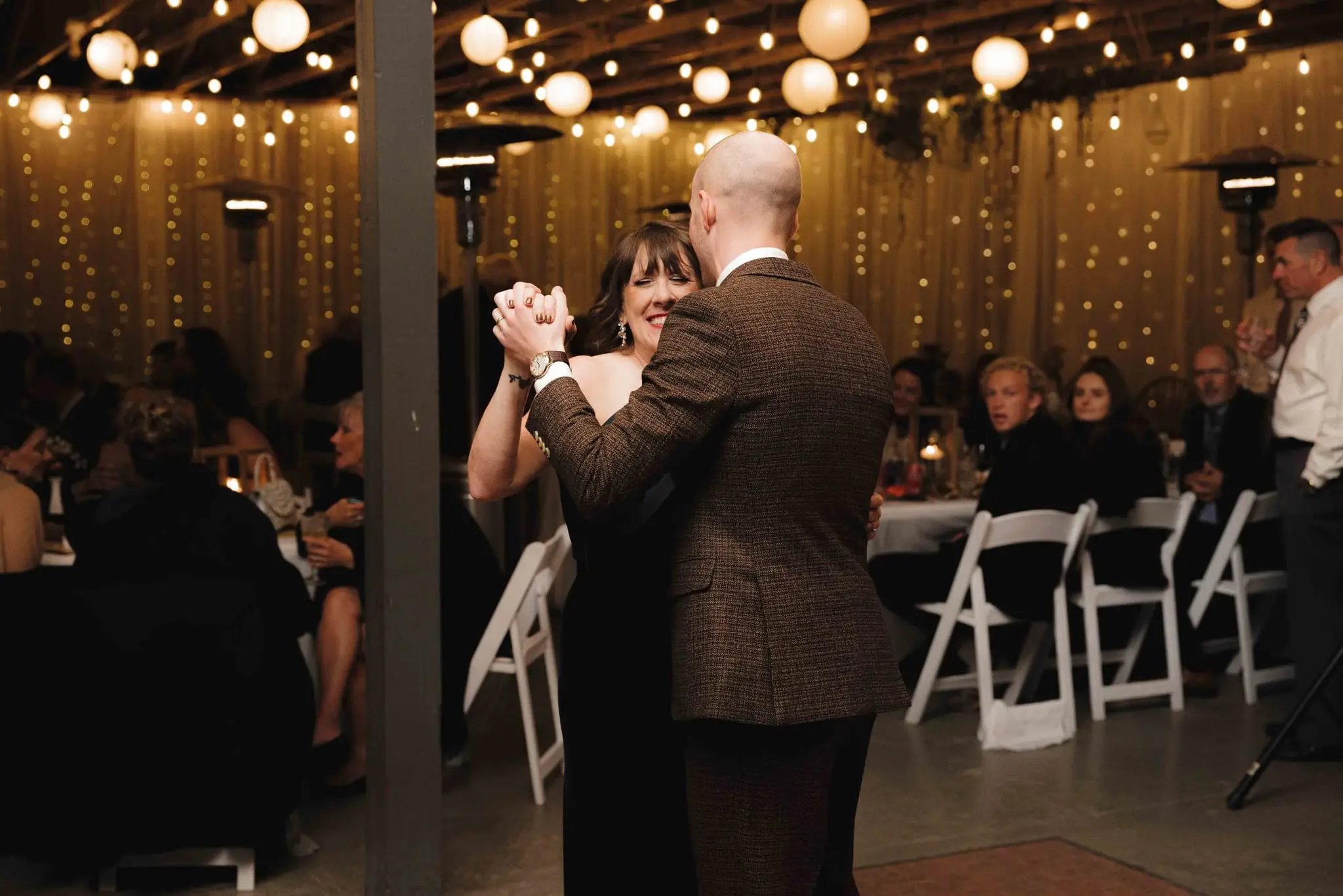 Elizabeth and Aidan wedding at Emerald Ridge Farm, Weaverville NC — the groom dancing with a guest under string lights at the reception