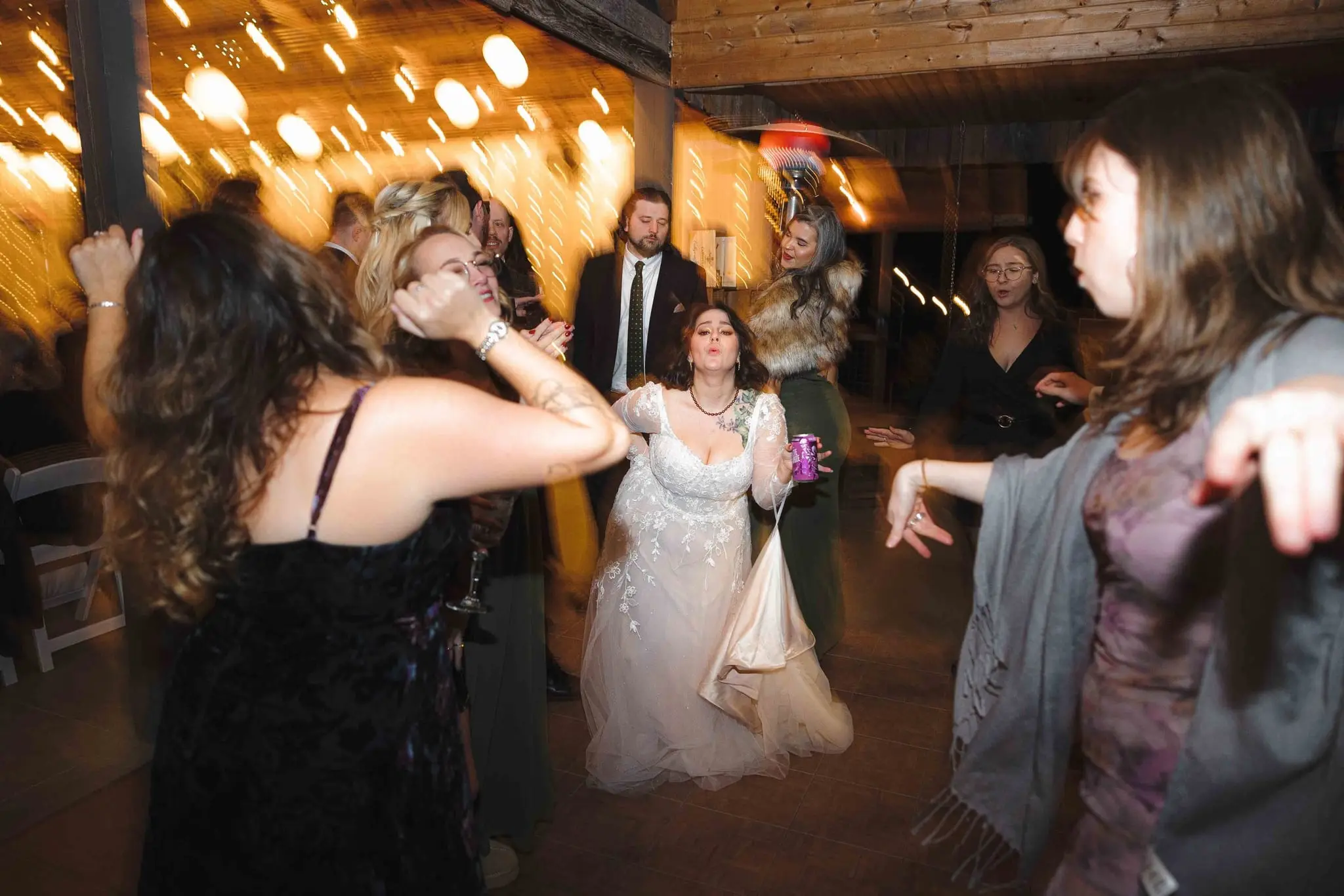 Bride dances between guests in a blur of warm lantern light
