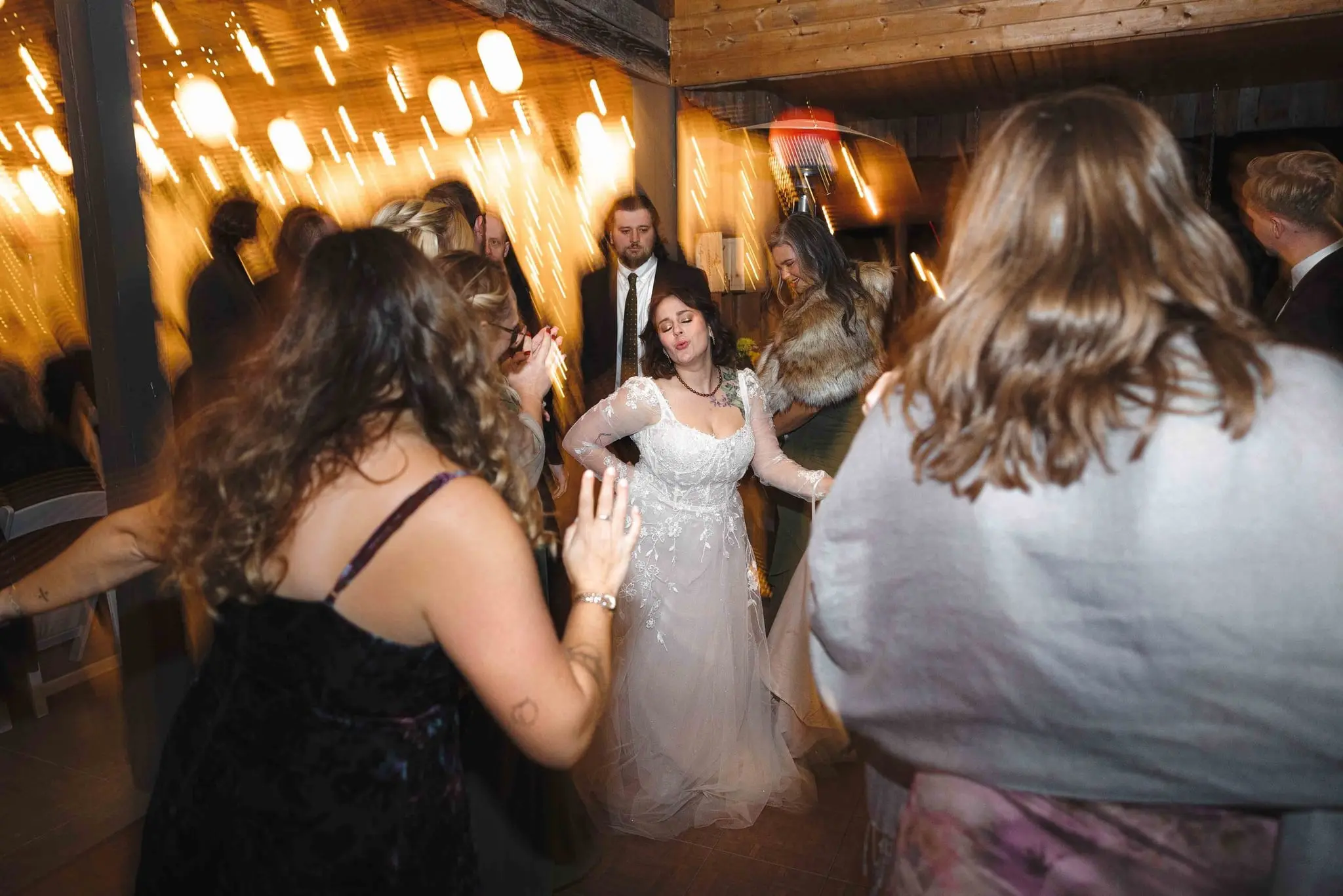 Bride sways with her eyes closed on the dance floor as guests move around her