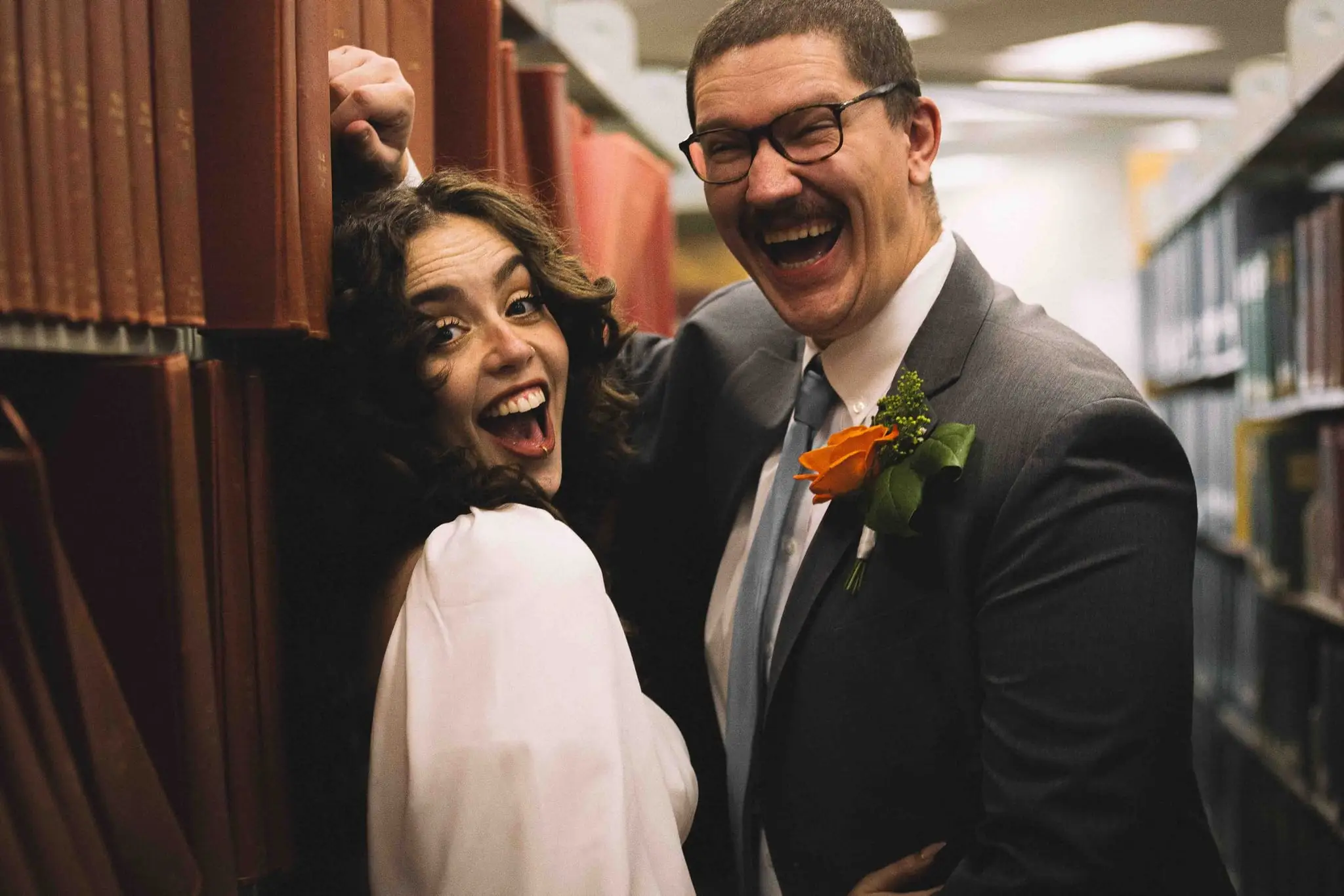 Giuliette and Will’s courthouse wedding day, Asheville NC — the couple laughing together among library shelves