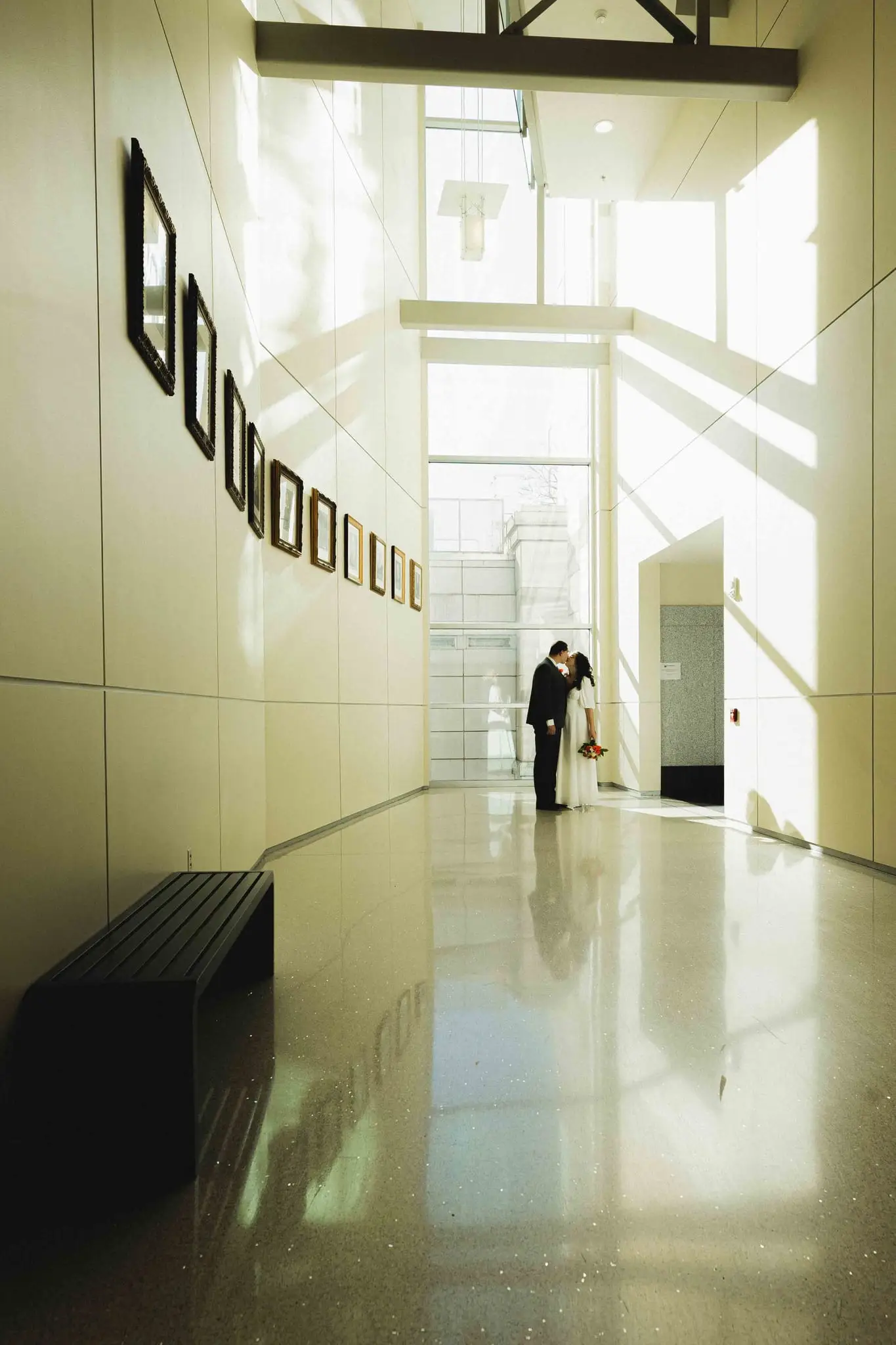 Giuliette and Will’s courthouse wedding day, Asheville NC — the couple as silhouettes in a bright modern hallway with large windows