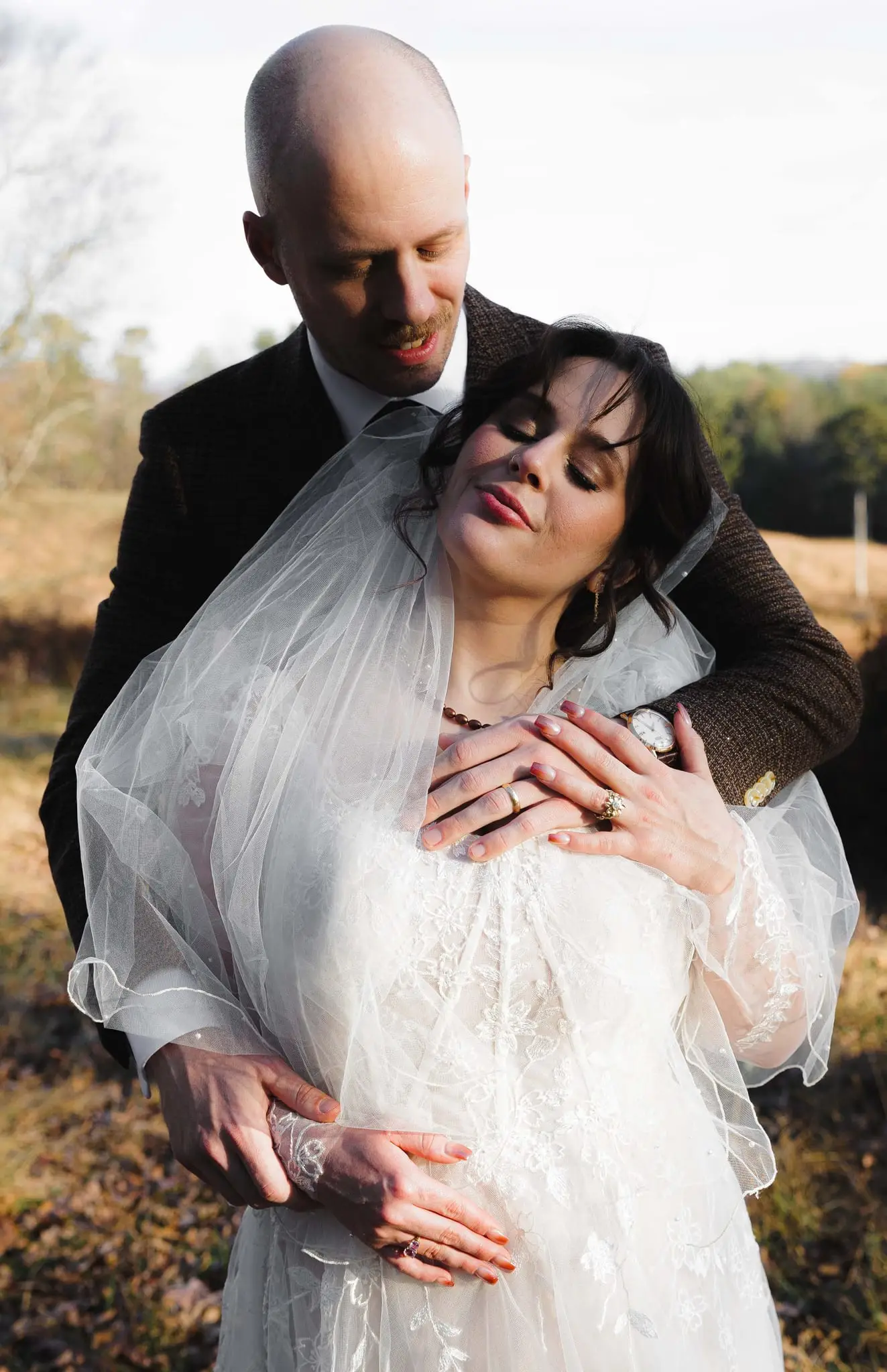 Elizabeth and Aidan wedding at Emerald Ridge Farm, Weaverville NC — the couple embracing in a golden field, the groom's arms around the bride