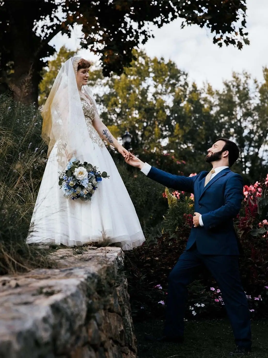 Hayden reaching up for Jessica's hand beside a stone wall at the Grand Bohemian, Greenville