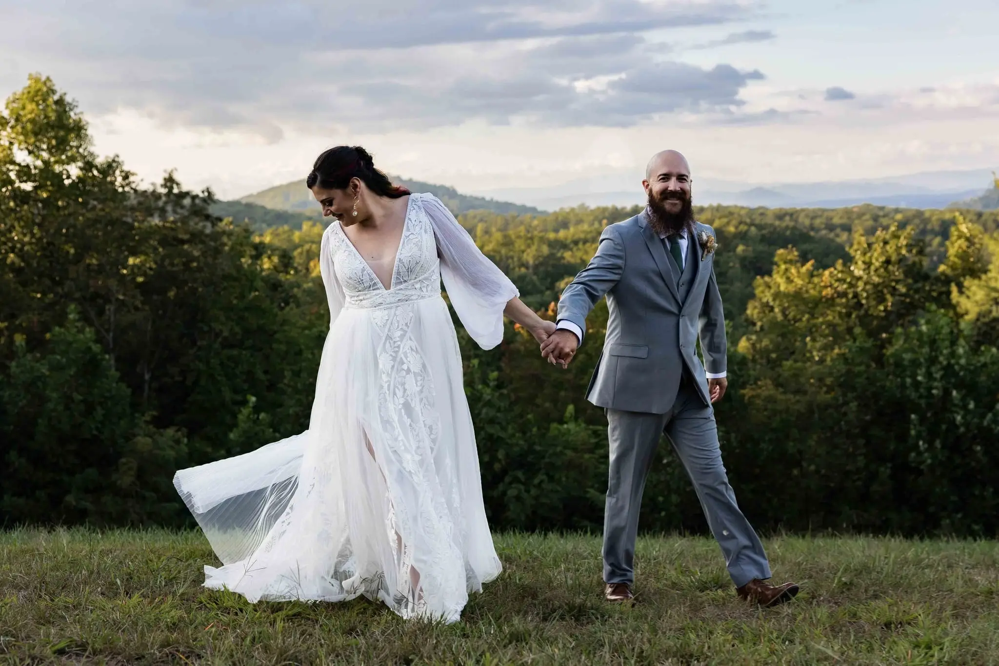 Bride's tulle skirt swirling as she walks hand in hand with the groom at golden hour