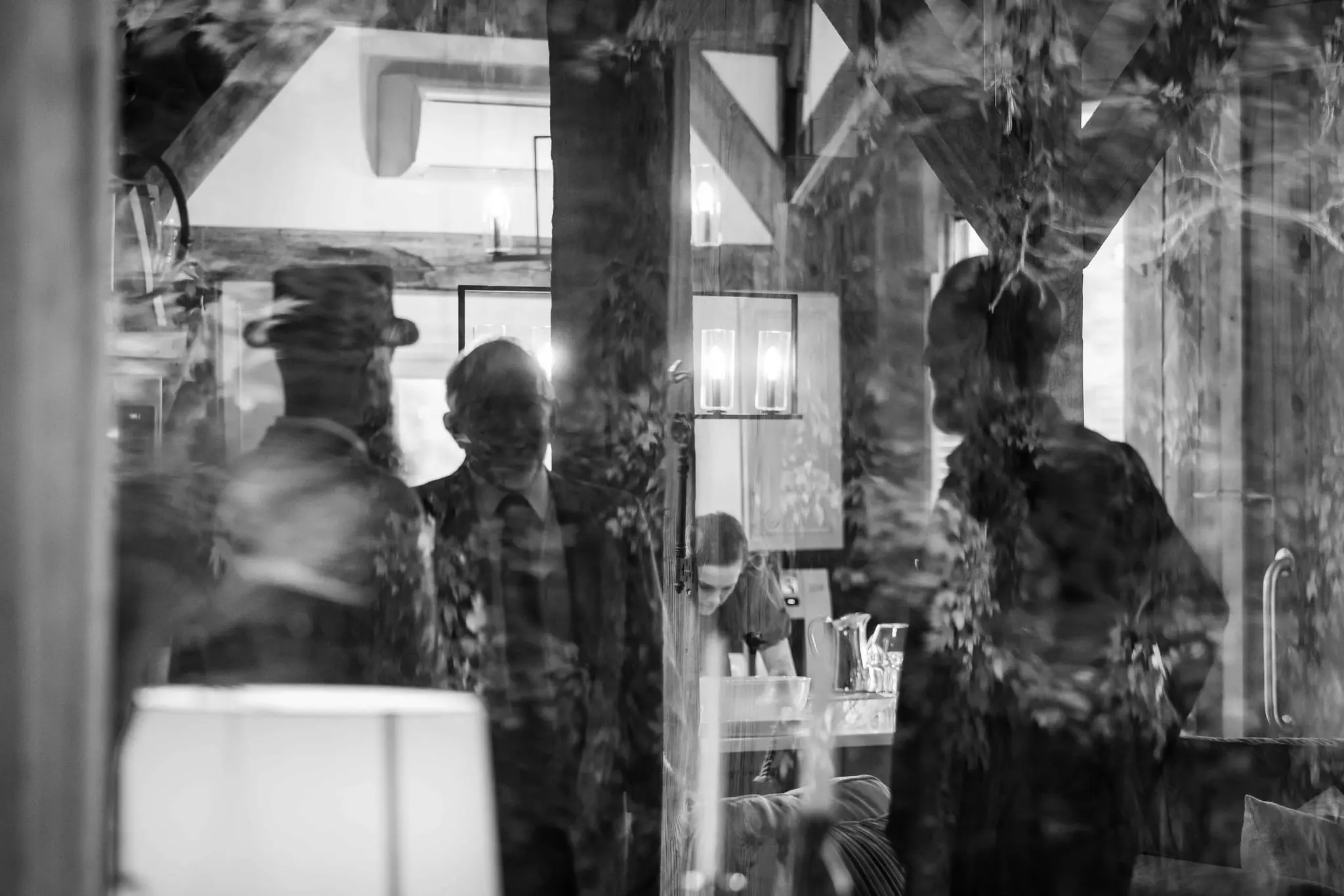 Black and white window reflections of guests inside a timber-framed reception space