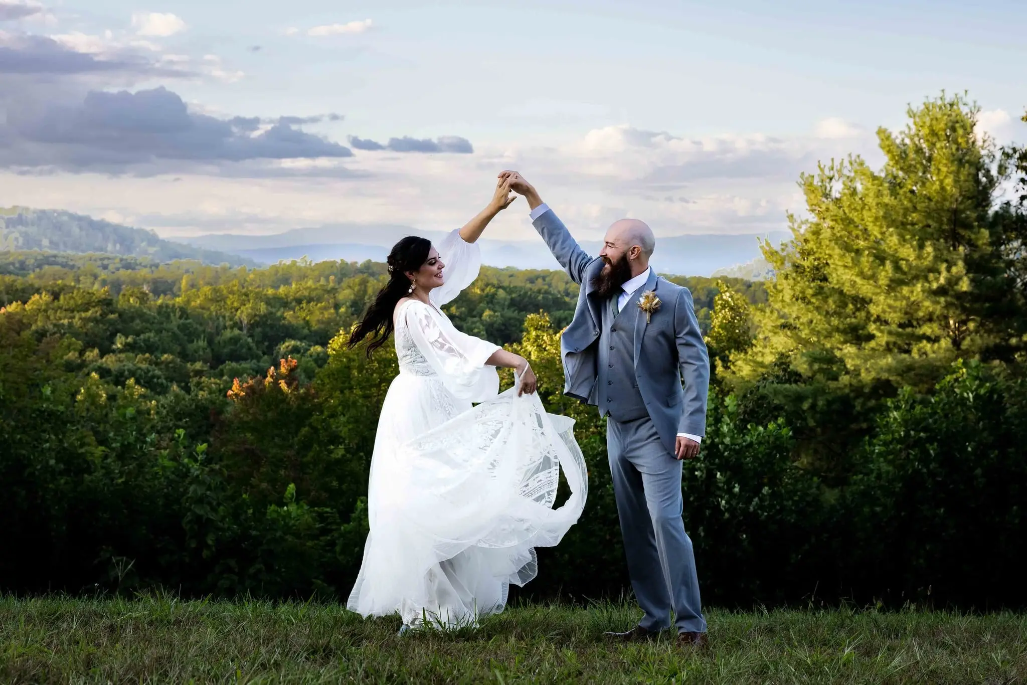 Groom spinning the bride under his arm on the Flanagan Estate overlook with Blue Ridge ridgelines behind