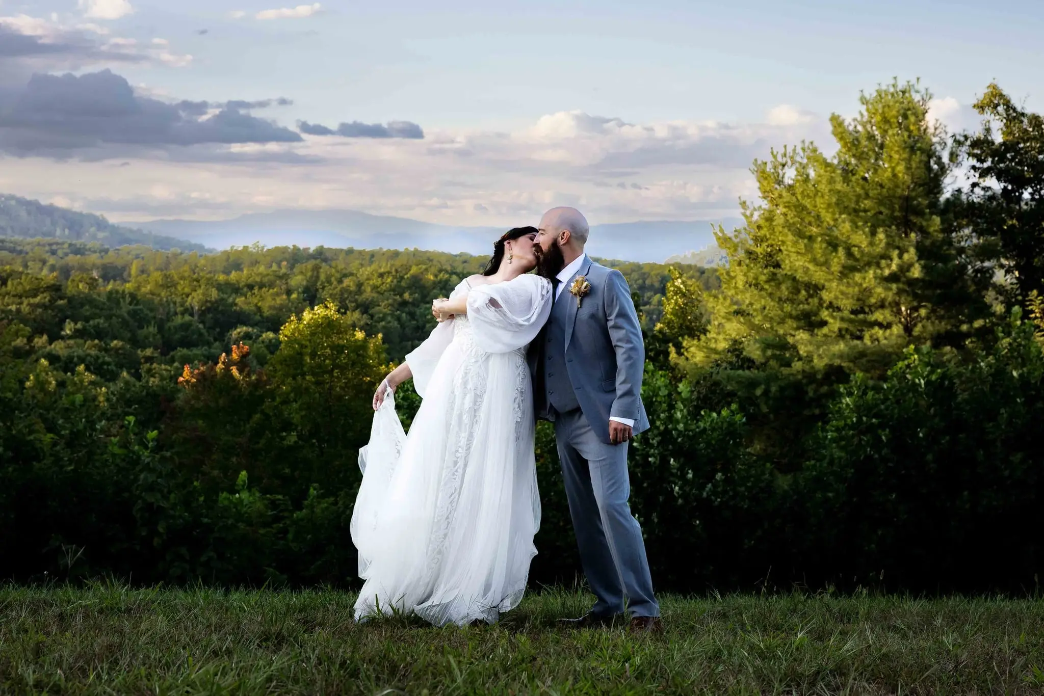 Couple sharing a kiss mid-dance on the overlook as her skirt swings