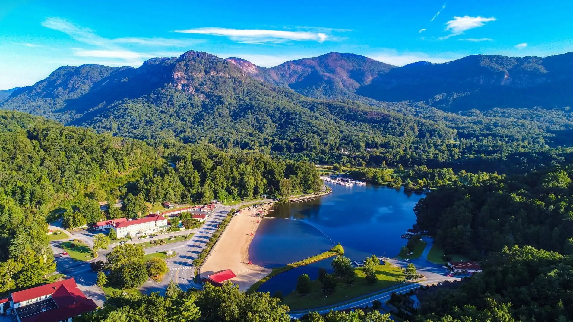 Aerial view of Lake Lure's beach and blue water ringed by forested mountains