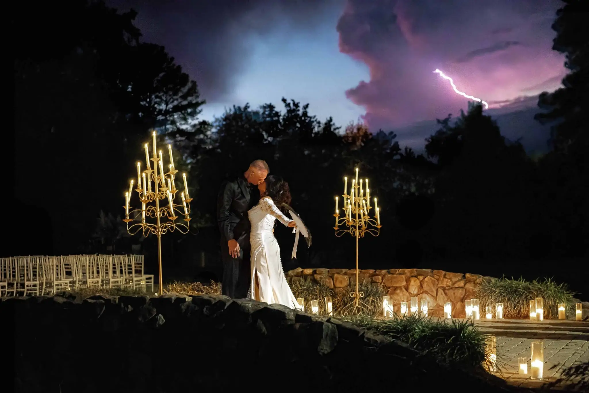 Couple kissing on a stone terrace among gold candelabras as lightning flashes in a purple storm sky